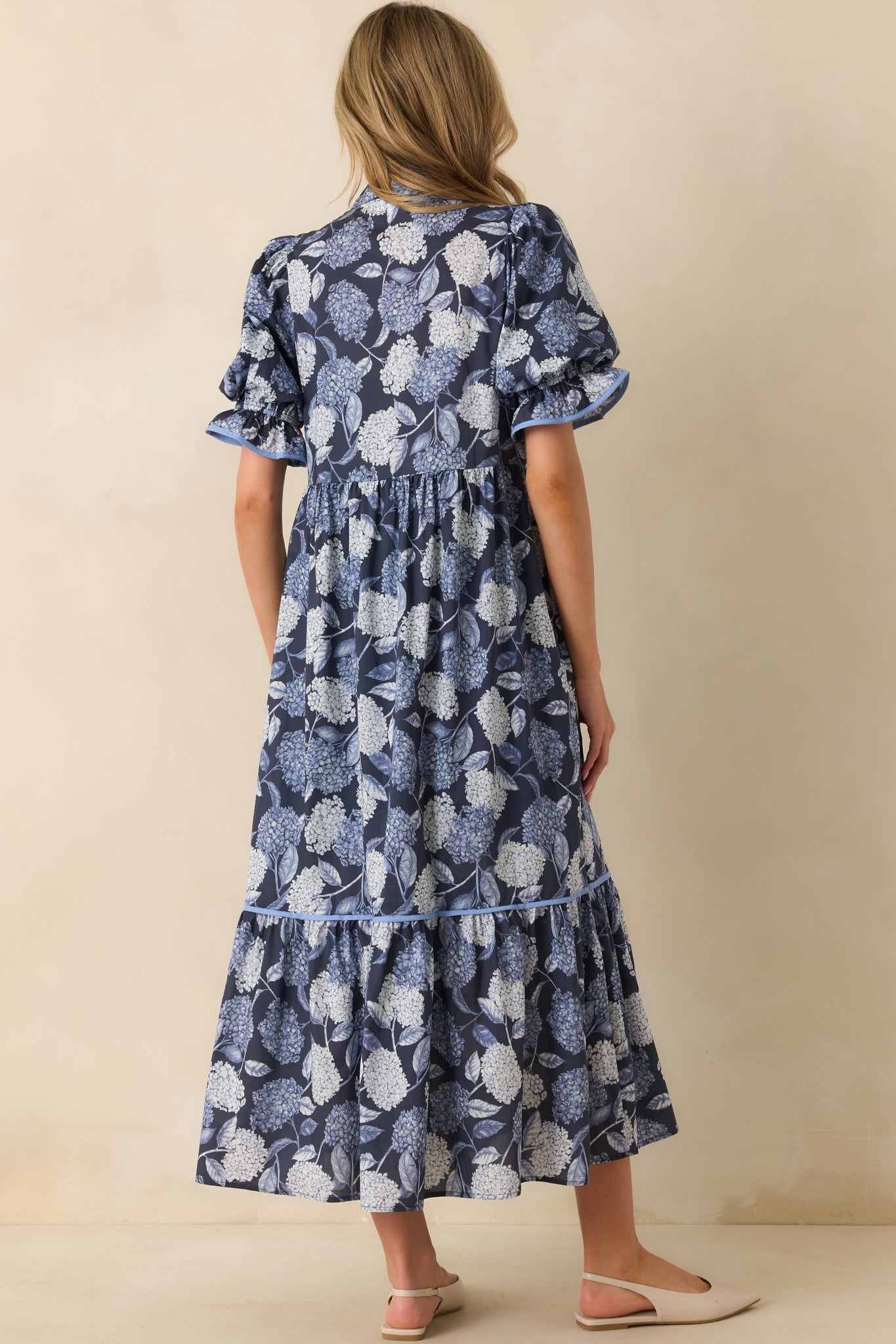 A back view of the floral maxi dress highlighting the puff sleeves, fitted bust, and flowing skirt.