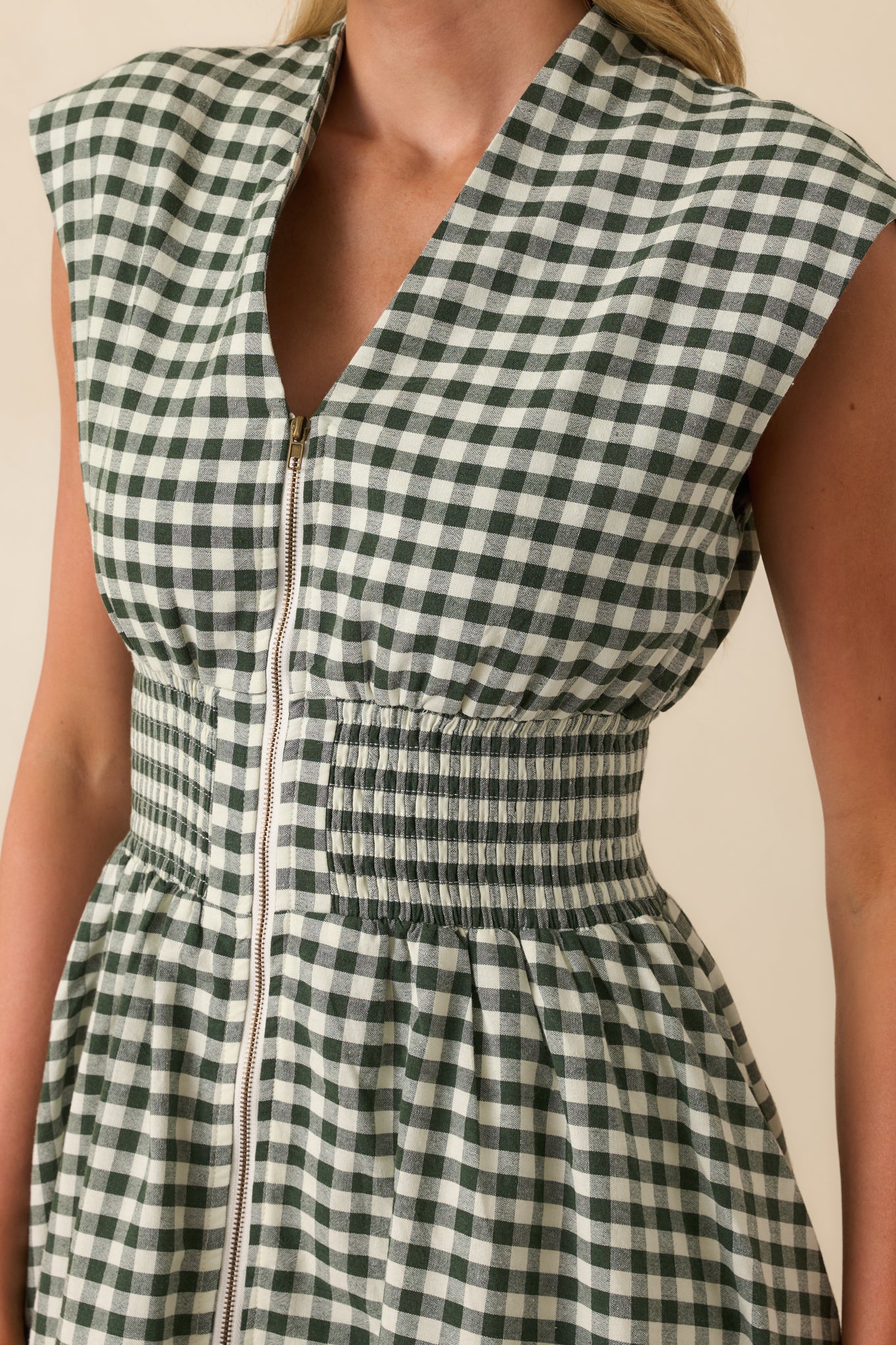 Close-up of the green gingham fabric, smocked waist, and zipper detail on the midi dress.