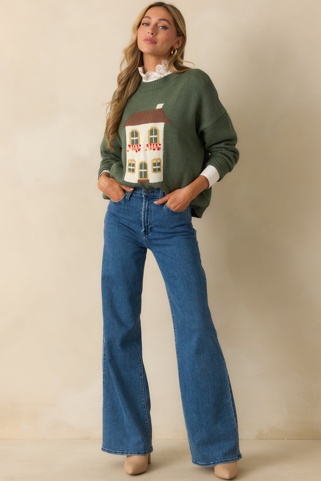 Front-facing view of green knit sweater featuring long sleeves, ribbed hems, and house graphic.