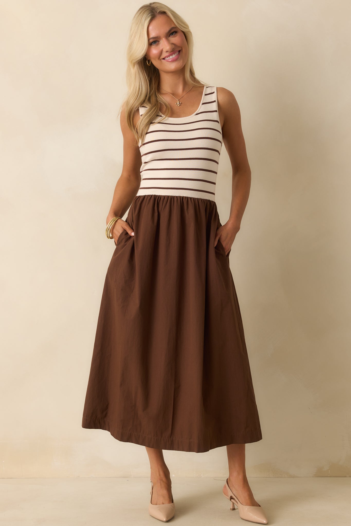 Front view of the maxi dress with a striped top and flowing solid brown skirt.