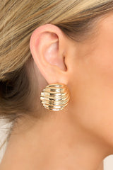 These earrings boast gold hardware in a circular shape with a wave-like texture, secured with a post backing for easy wearing