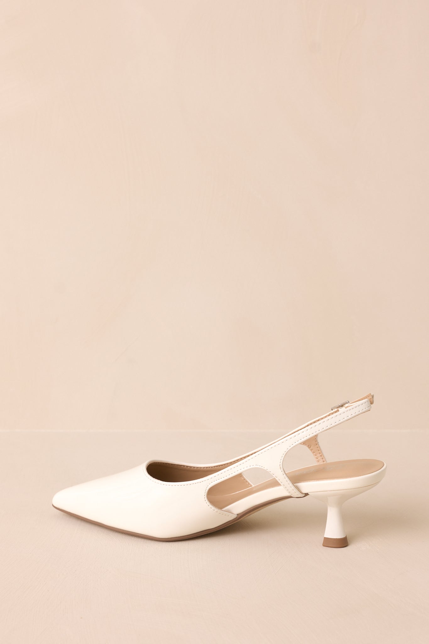 Gold buckle white patent pointed-toe heel with side cutout inner side view.