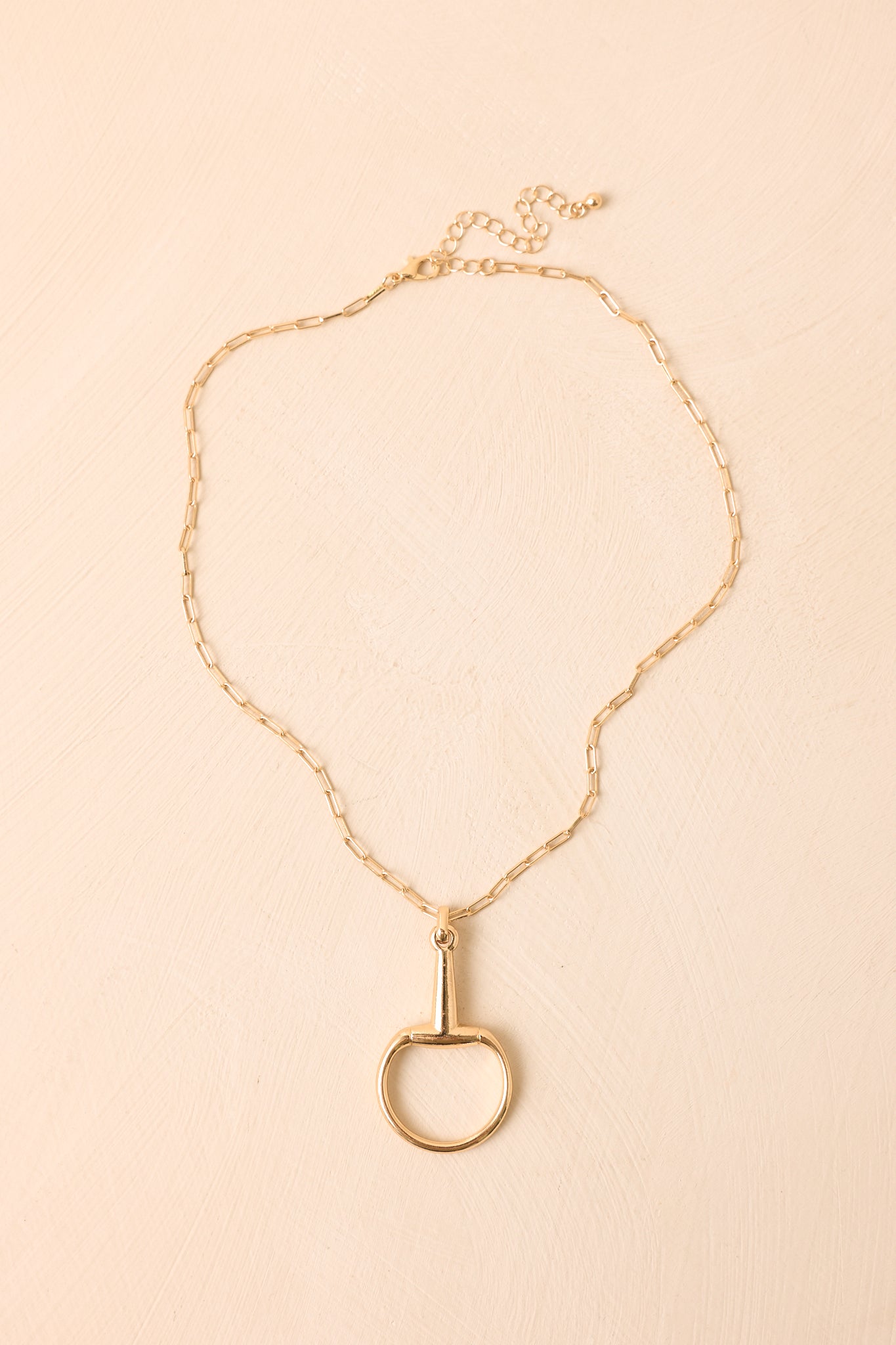 Gold paperclip chain necklace featuring a polished equestrian-inspired stirrup pendant.