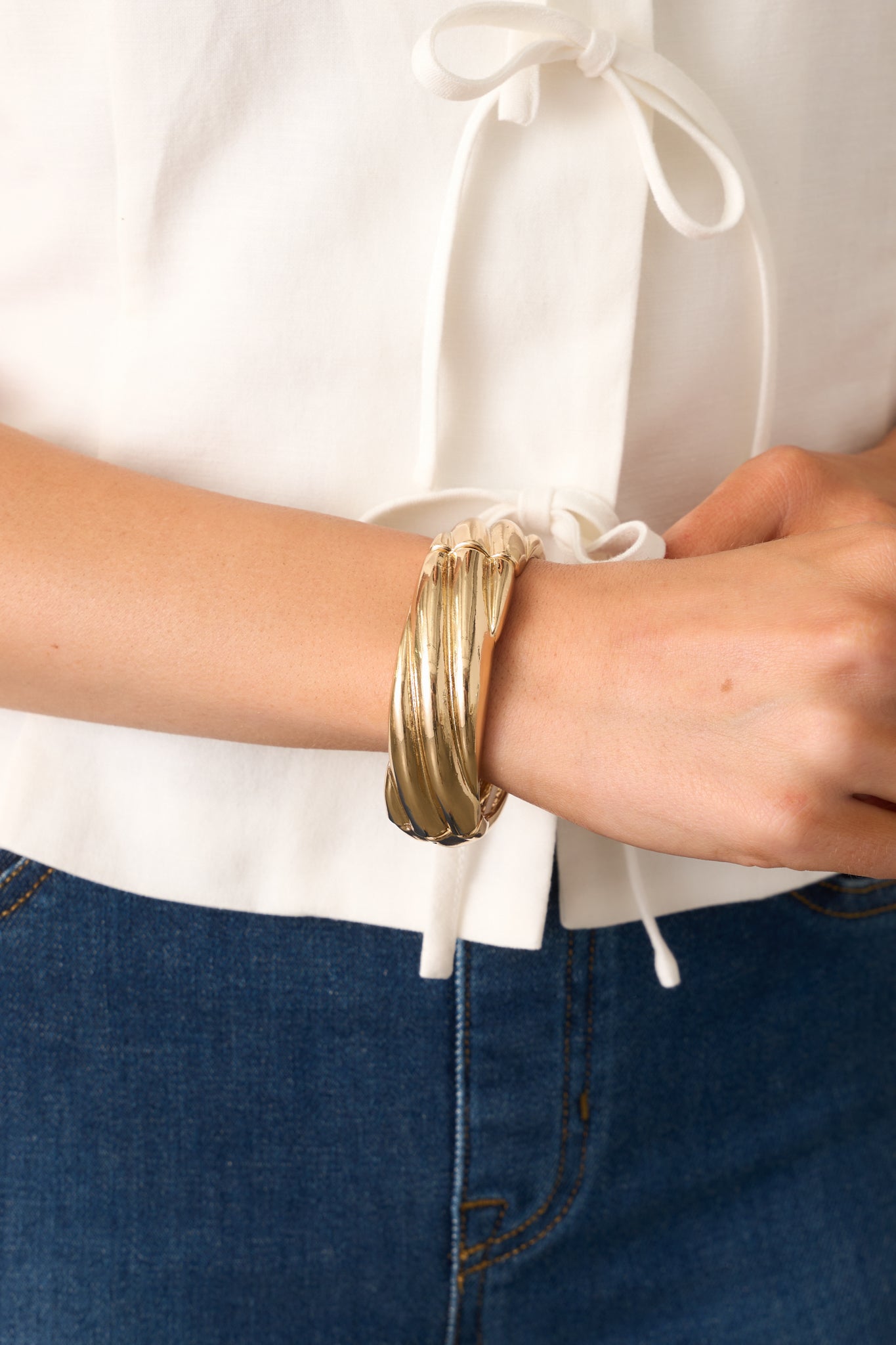 A gleaming gold bracelet with a textured design, featuring flexible elastic bands for an easy, slip-on fit.