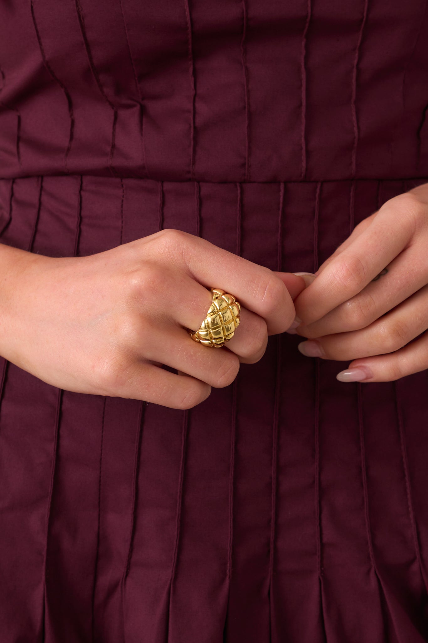 Close-up of gold ring showing intricate raised woven texture and open cuff construction.