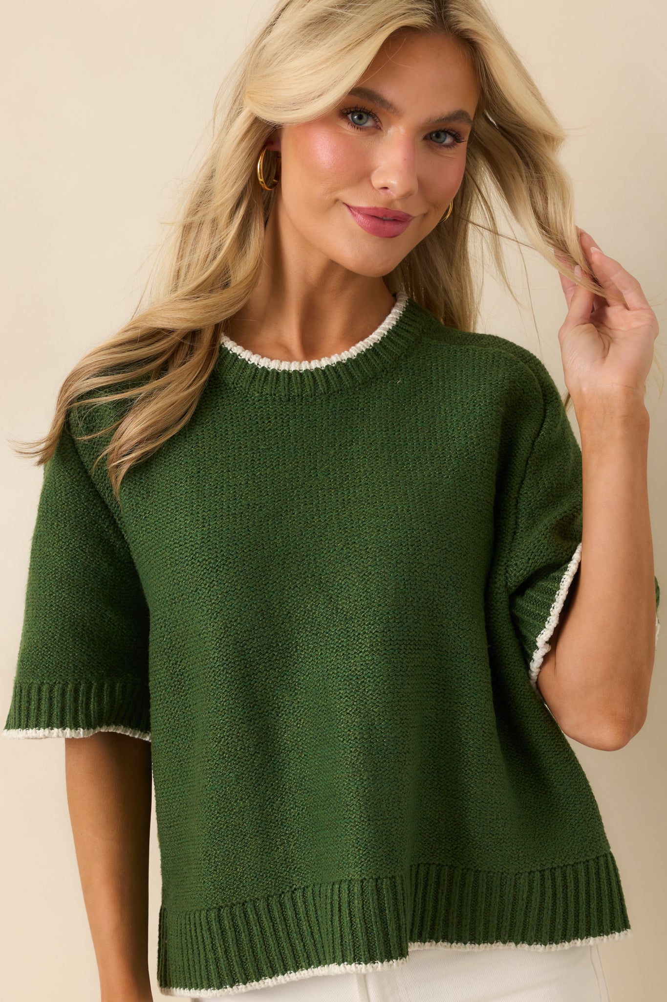 Cropped image showing ribbed hem and textured knit fabric of green sweater
