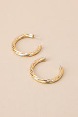 Top view of these earrings feature gold hardware, a twist like design, and a secure post backing.