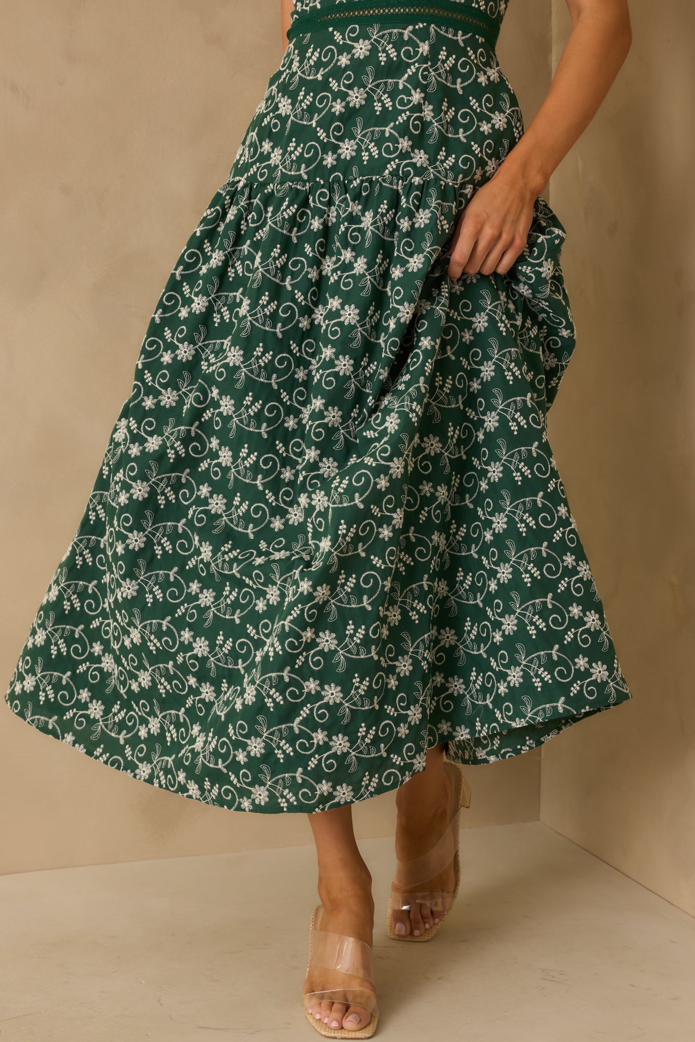 Cropped view of the hunter green maxi dress’s lower half, showing the flow of the drop waist skirt.