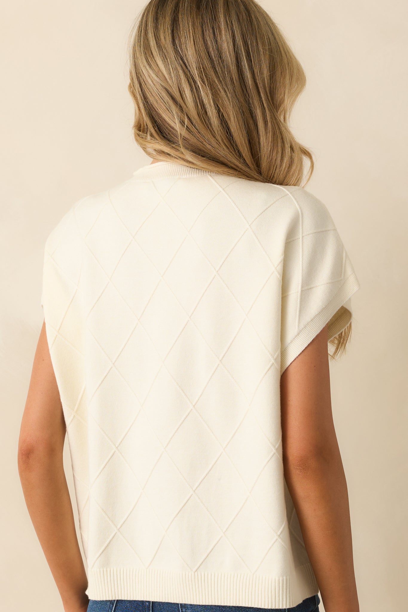 Rear view of the ivory sweater showing dolman sleeves and straight hem.