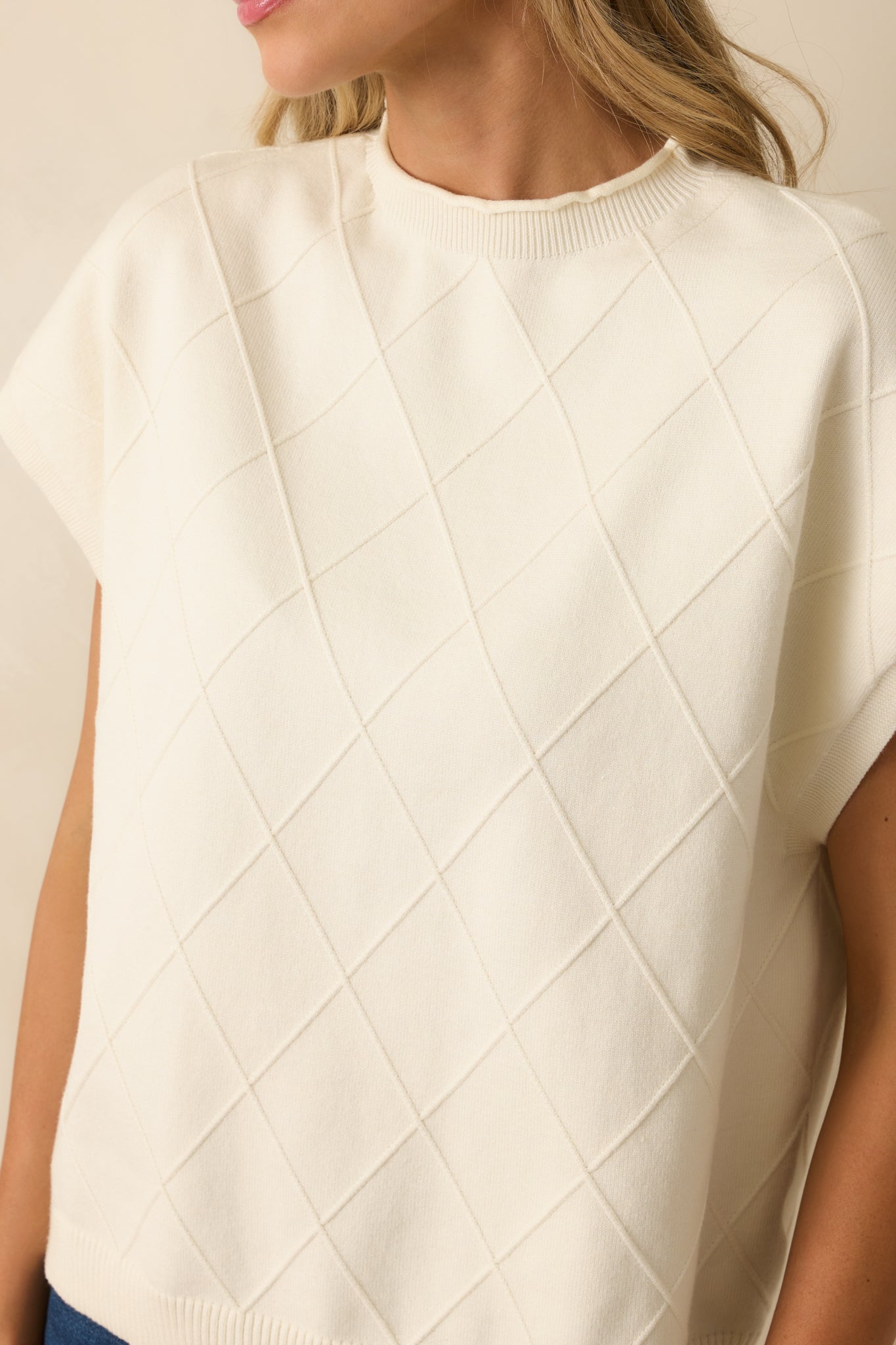 Close-up of the argyle stitch pattern and cuff detailing on the ivory sweater.