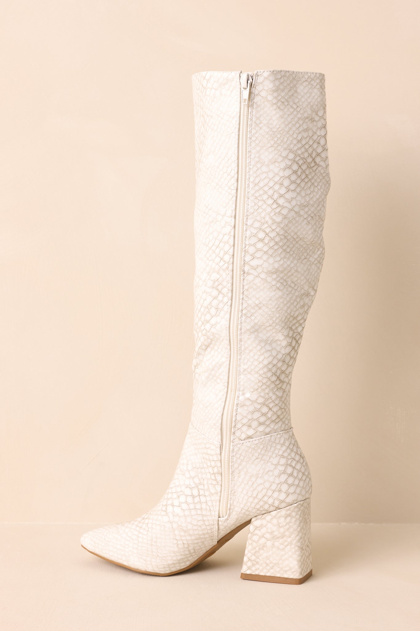Ivory boots displayed on a beige background showing the full side profile with its zipper closure.