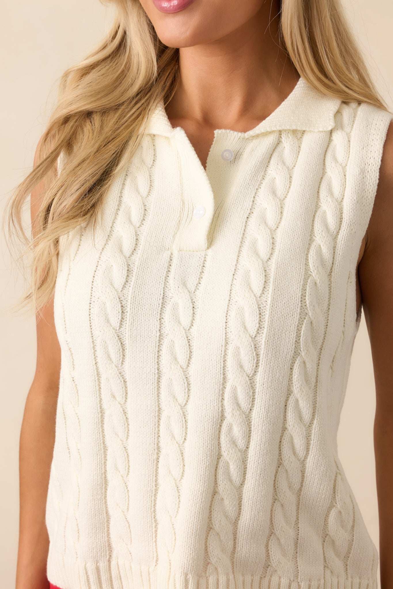 A zoomed-in shot highlighting the textured cable knit fabric and fine ribbing along the neckline and button placket.