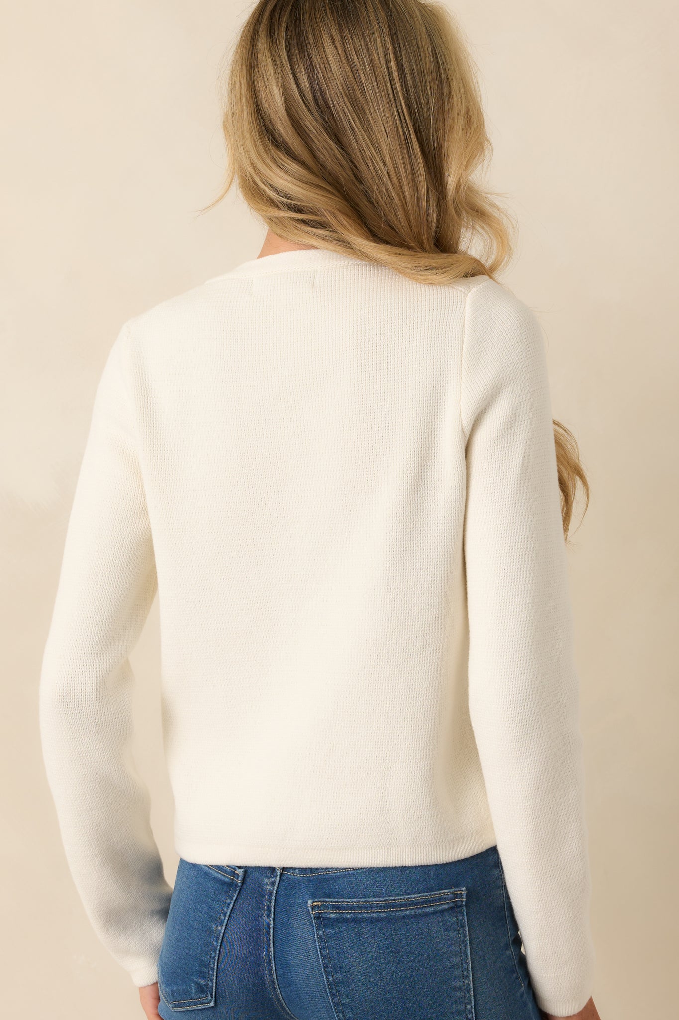 Back view of ivory cardigan with long sleeves and smooth knit fabric.