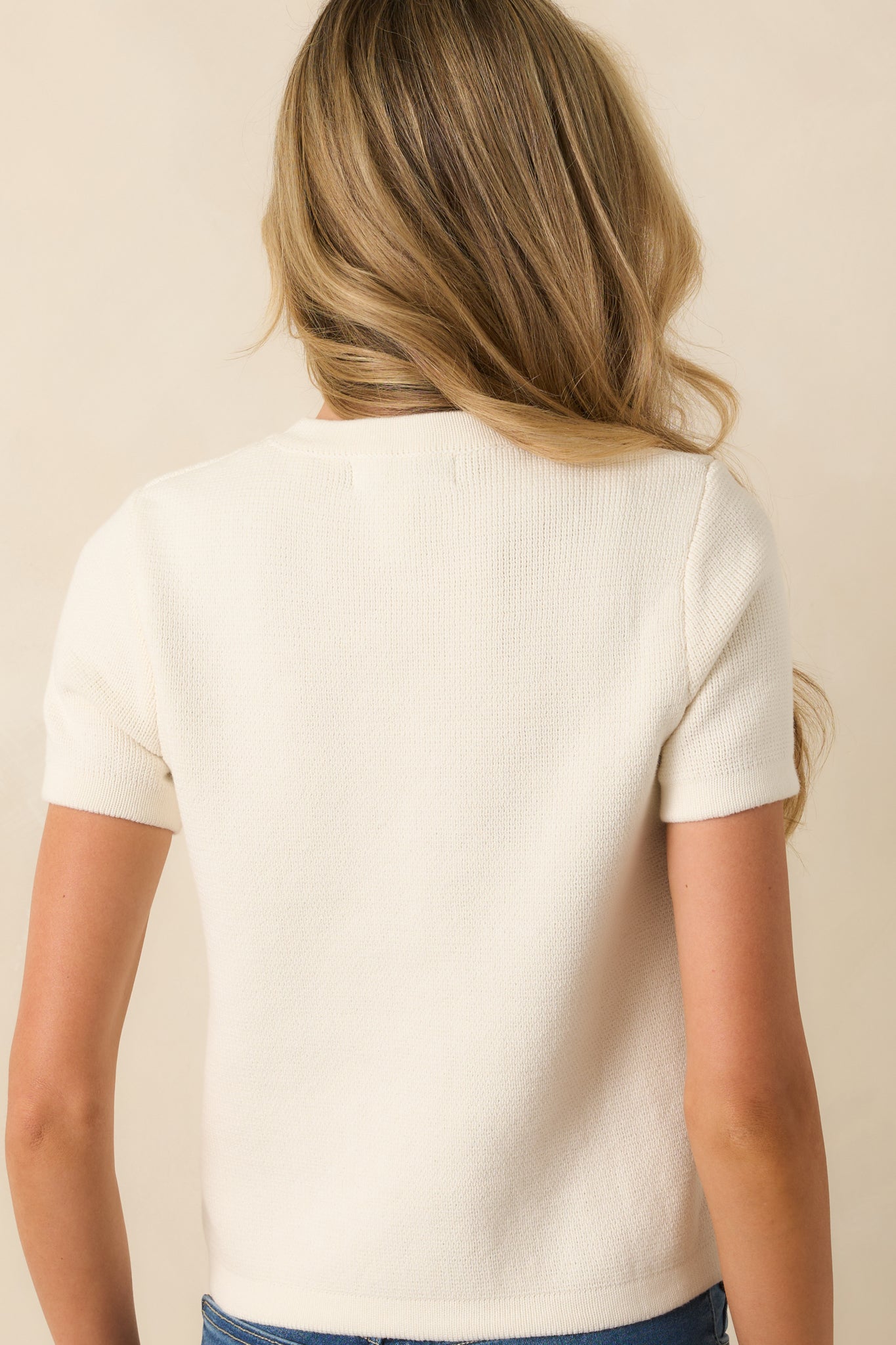 Back view of ivory sweater with short sleeves and knit construction.