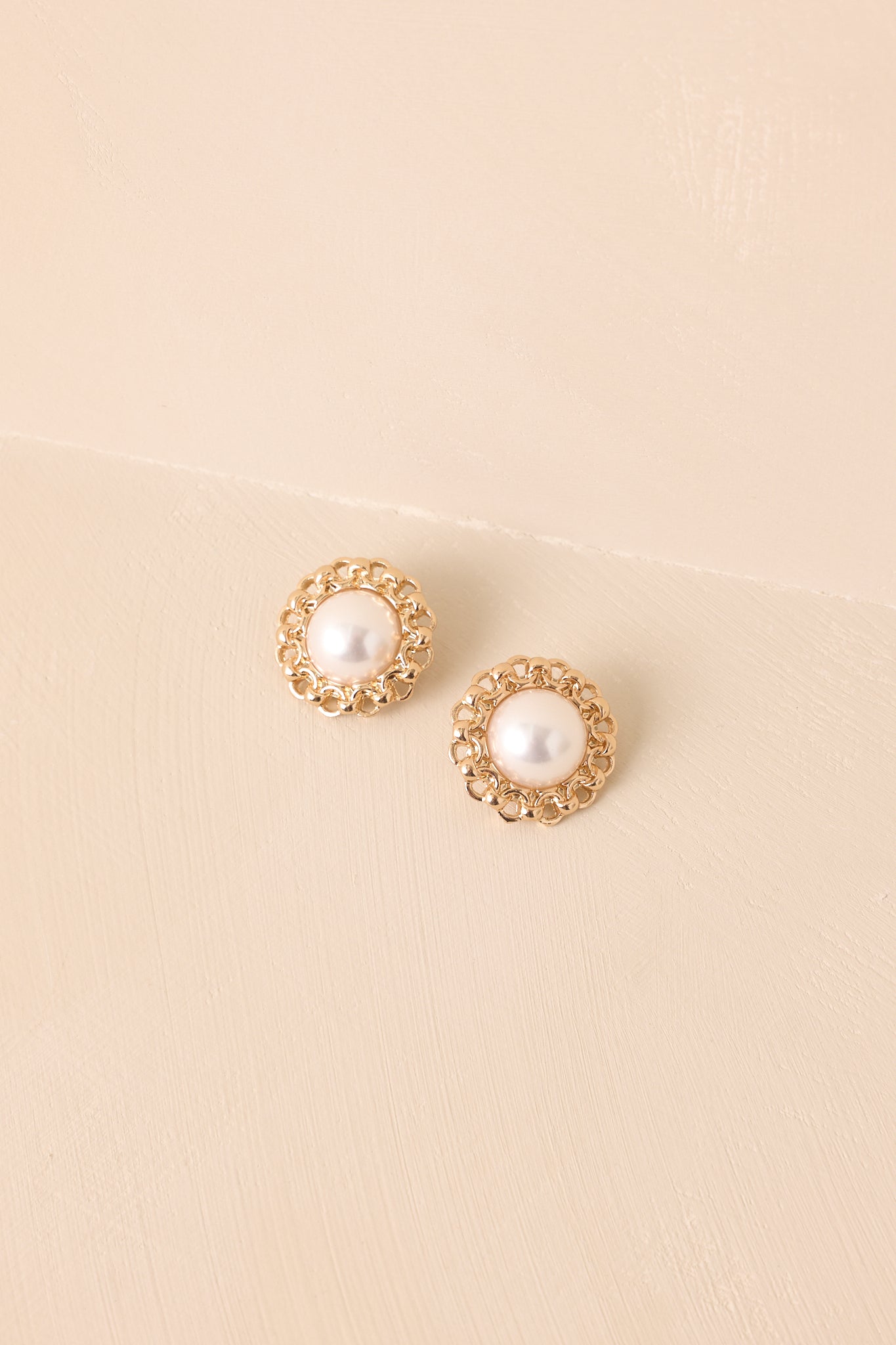 Pair of ivory faux pearl earrings with gold chain trim and post backings.