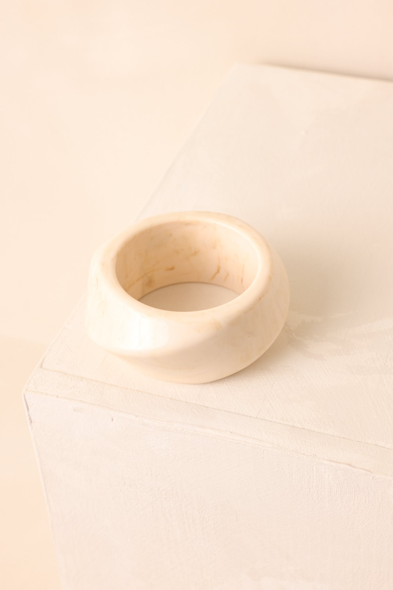 A detailed shot of the ivory chunky bangle emphasizing its marbled acrylic texture and polished glossy shine.