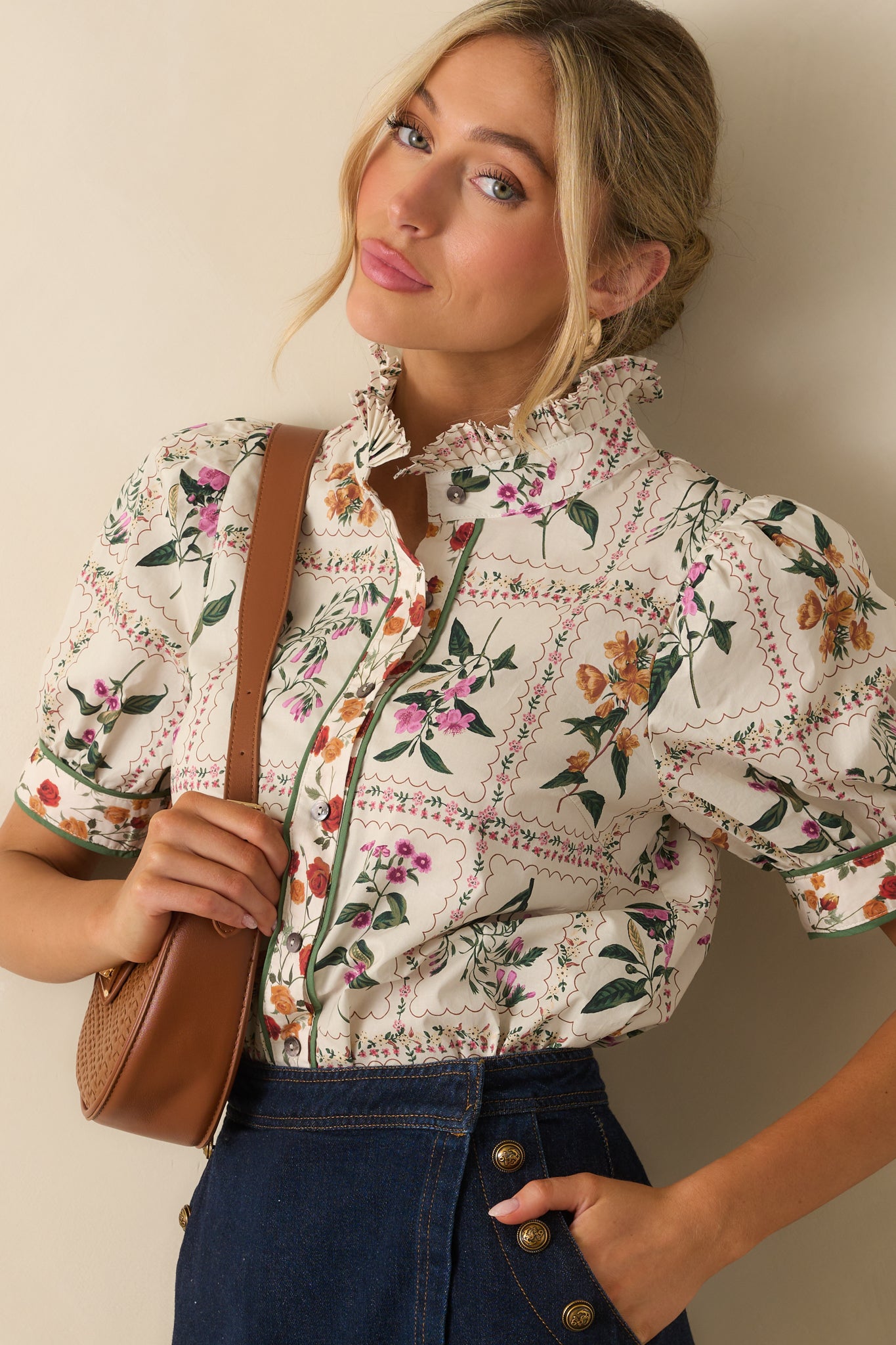 Close-up showing the pleated ruffle collar, button front, and multicolor patchwork floral print on the ivory top.