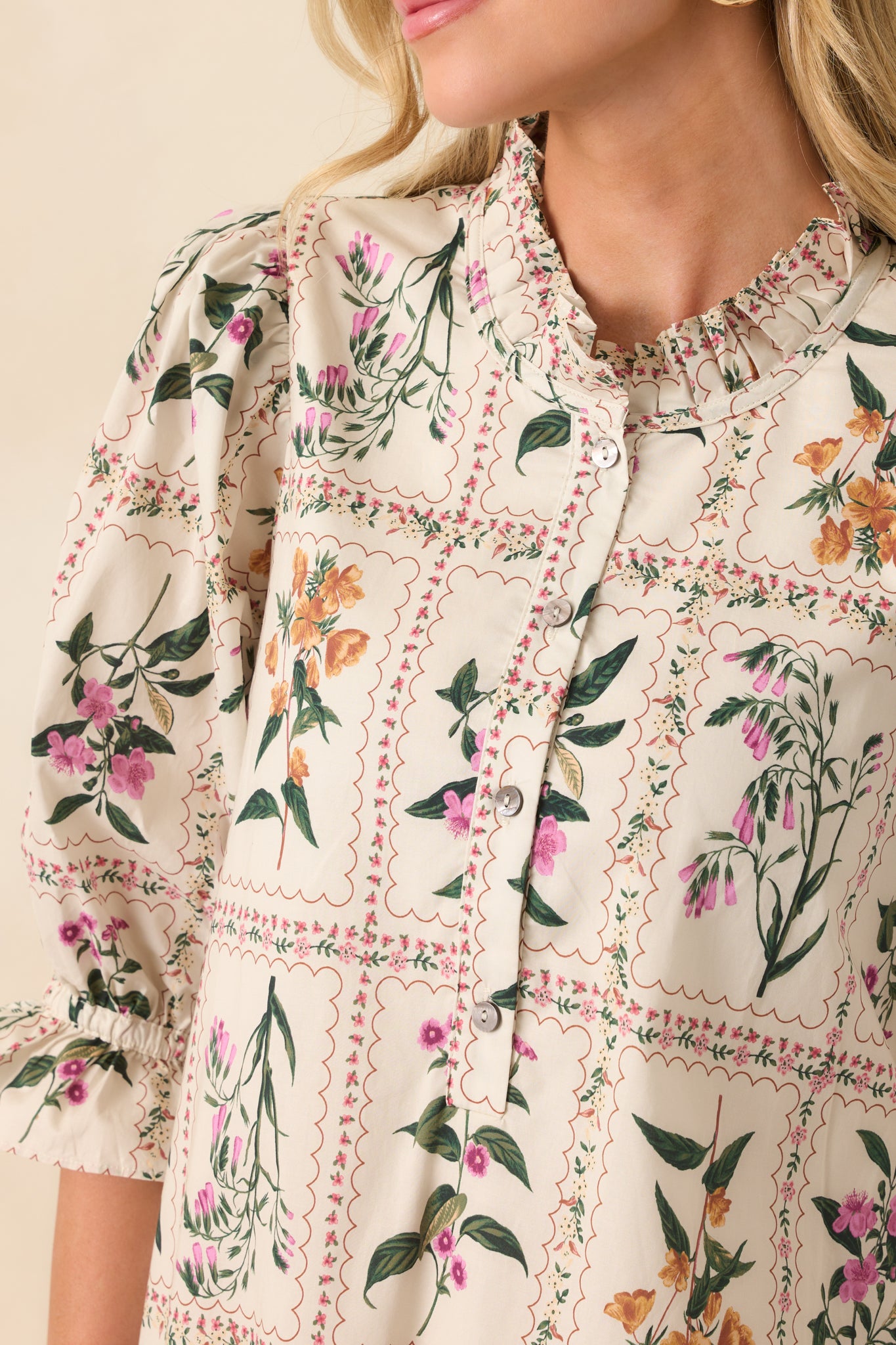 A close-up of the round neckline with ruffle trim and top buttons of the quarter button front.