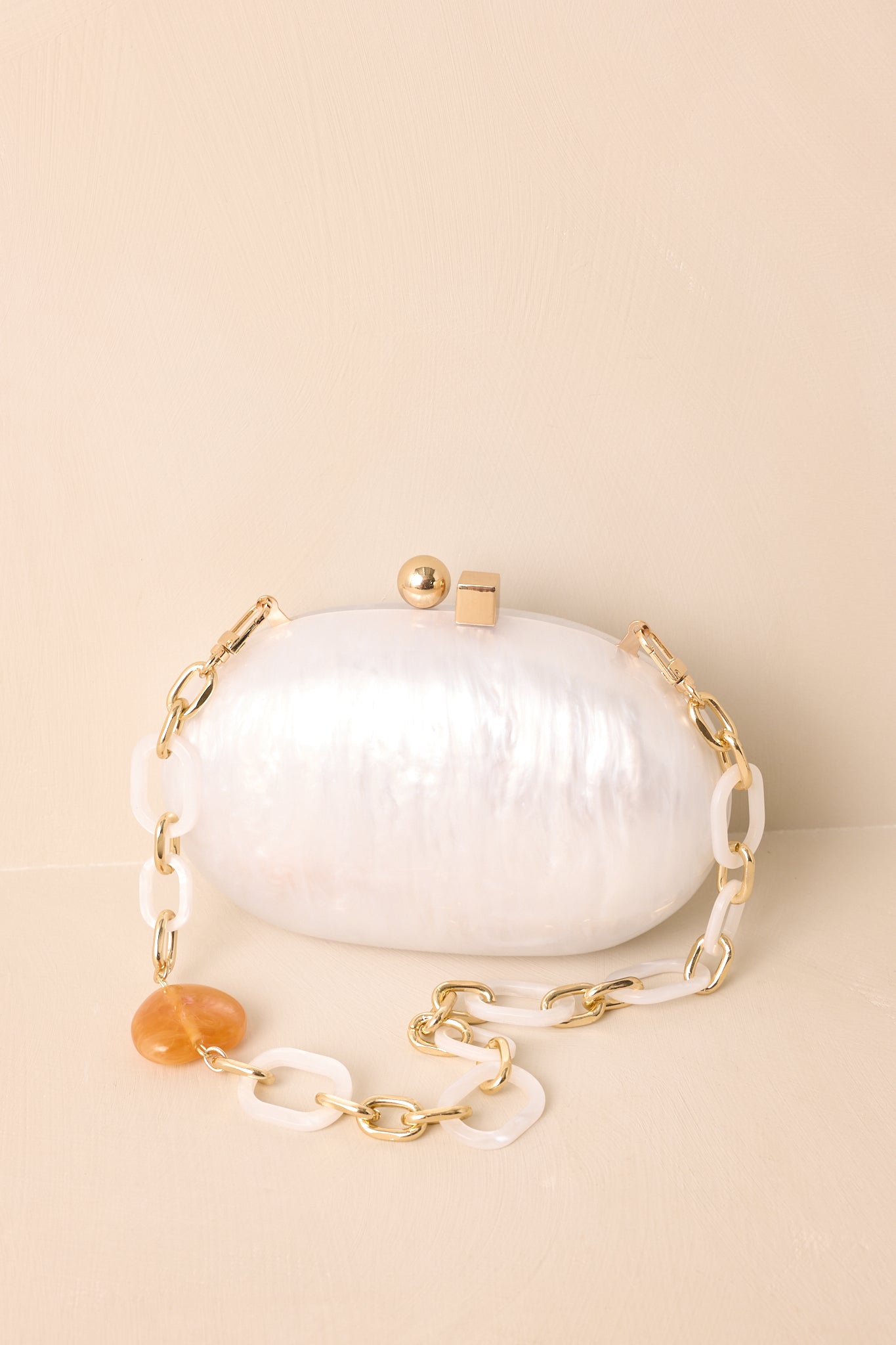 Close view of the pearlescent finish and gold box clasp on the ivory clutch.