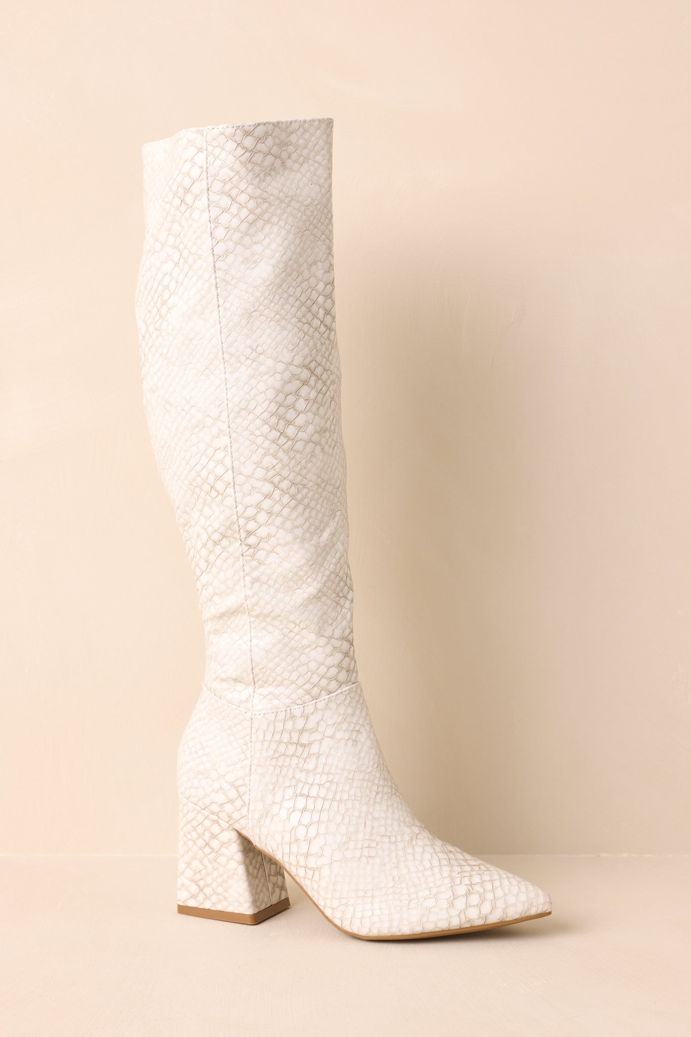 Ivory snakeskin embossed boots with a pointed toe and block heel showcased in a sleek side view.