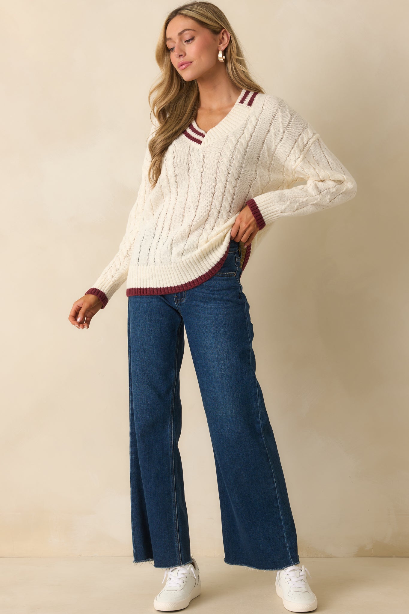 Ivory sweater with a deep V-neckline and burgundy contrast trim.