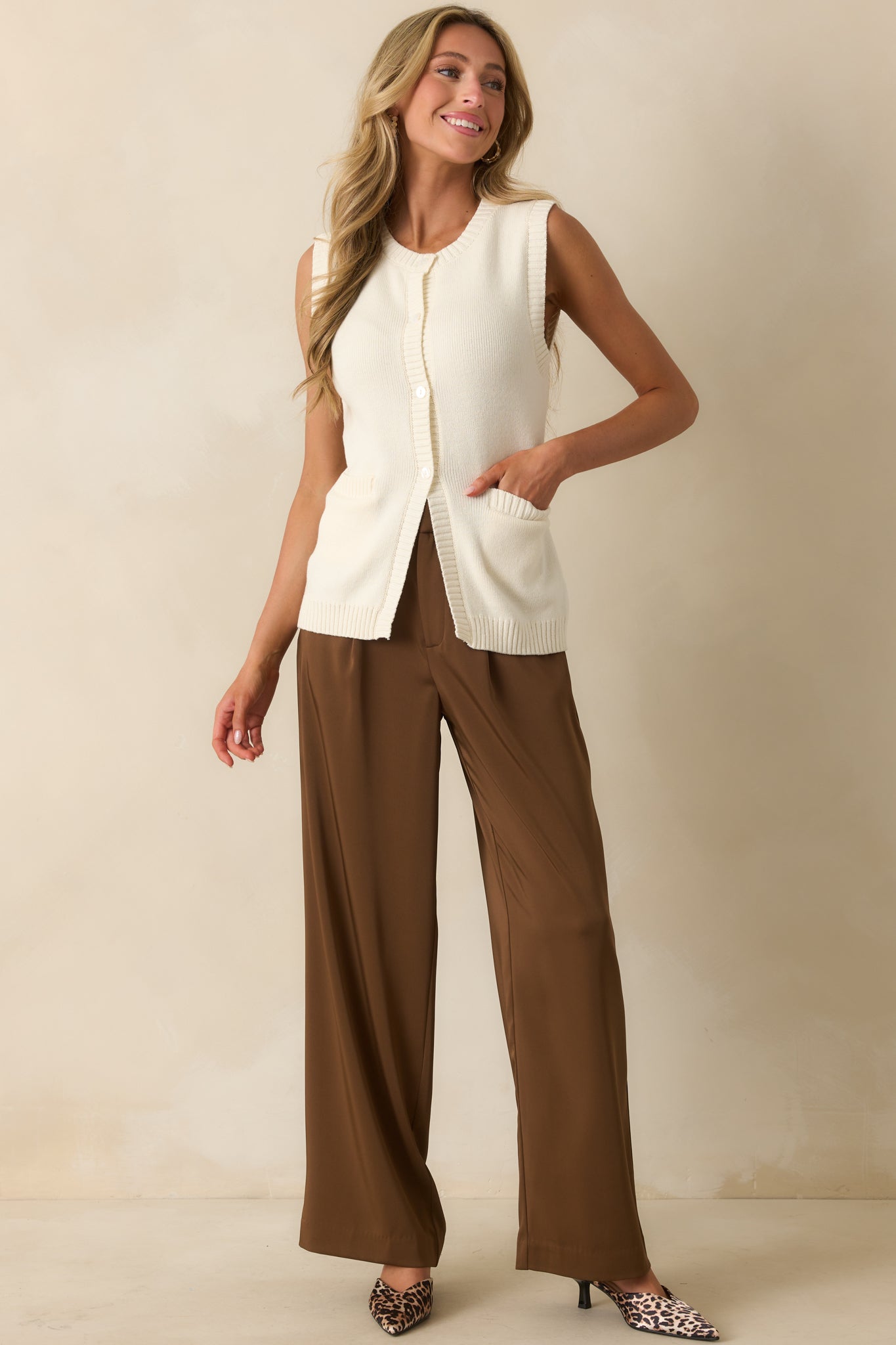 Ivory sweater vest with a crew neckline and functional button front placket.