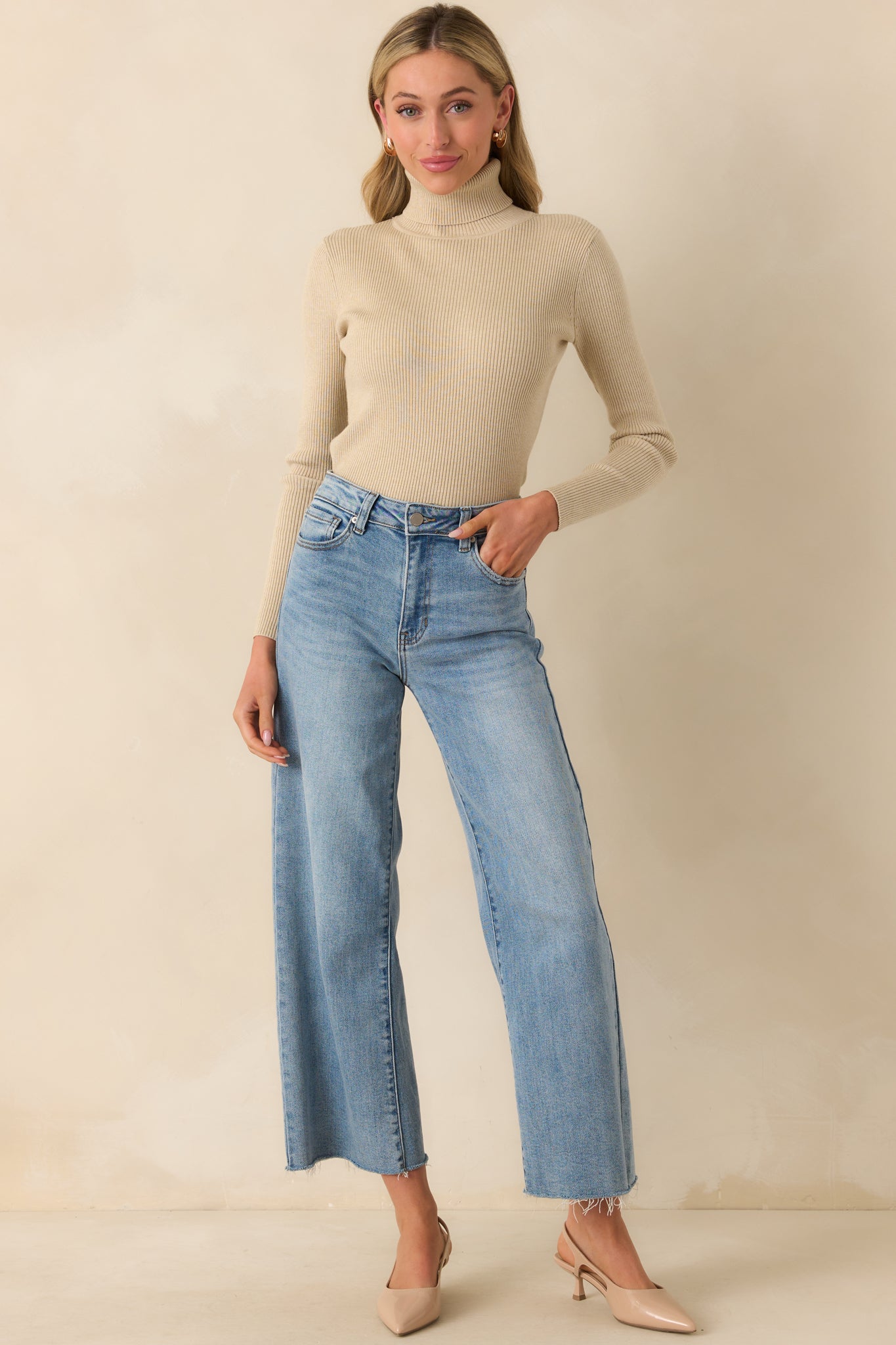 Full body angled shot highlighting the relaxed drape and long sleeve length of the ribbed sweater.