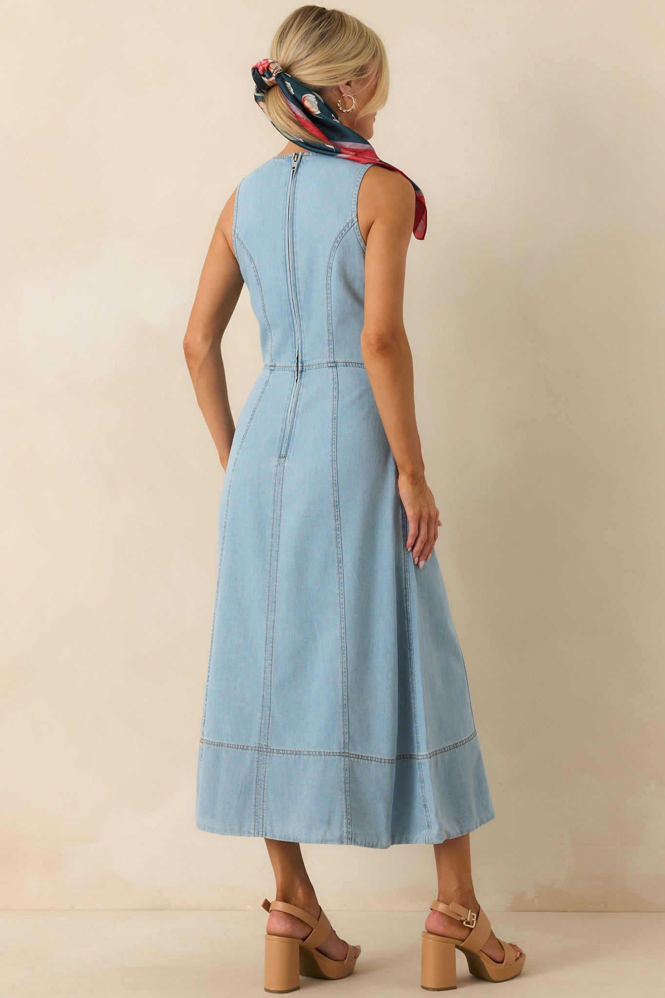 Rear view of light wash chambray midi dress with sleeveless cut, panelled seams, and back zipper closure.