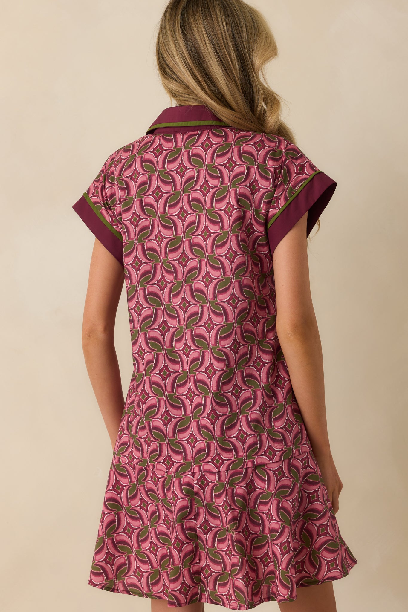Rear view of mauve geometric print mini dress with tiered skirt and wine purple accents.