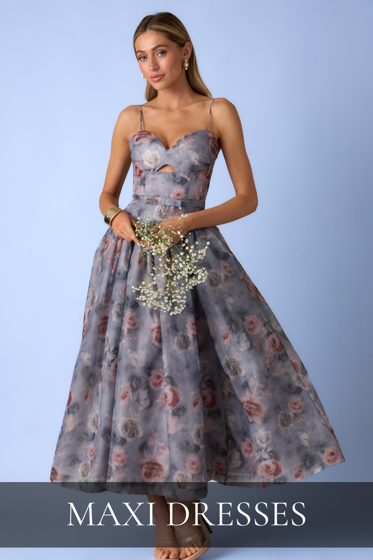 Woman wearing a floral maxi dress holding delicate flowers, linking to the Maxi Dresses shop.