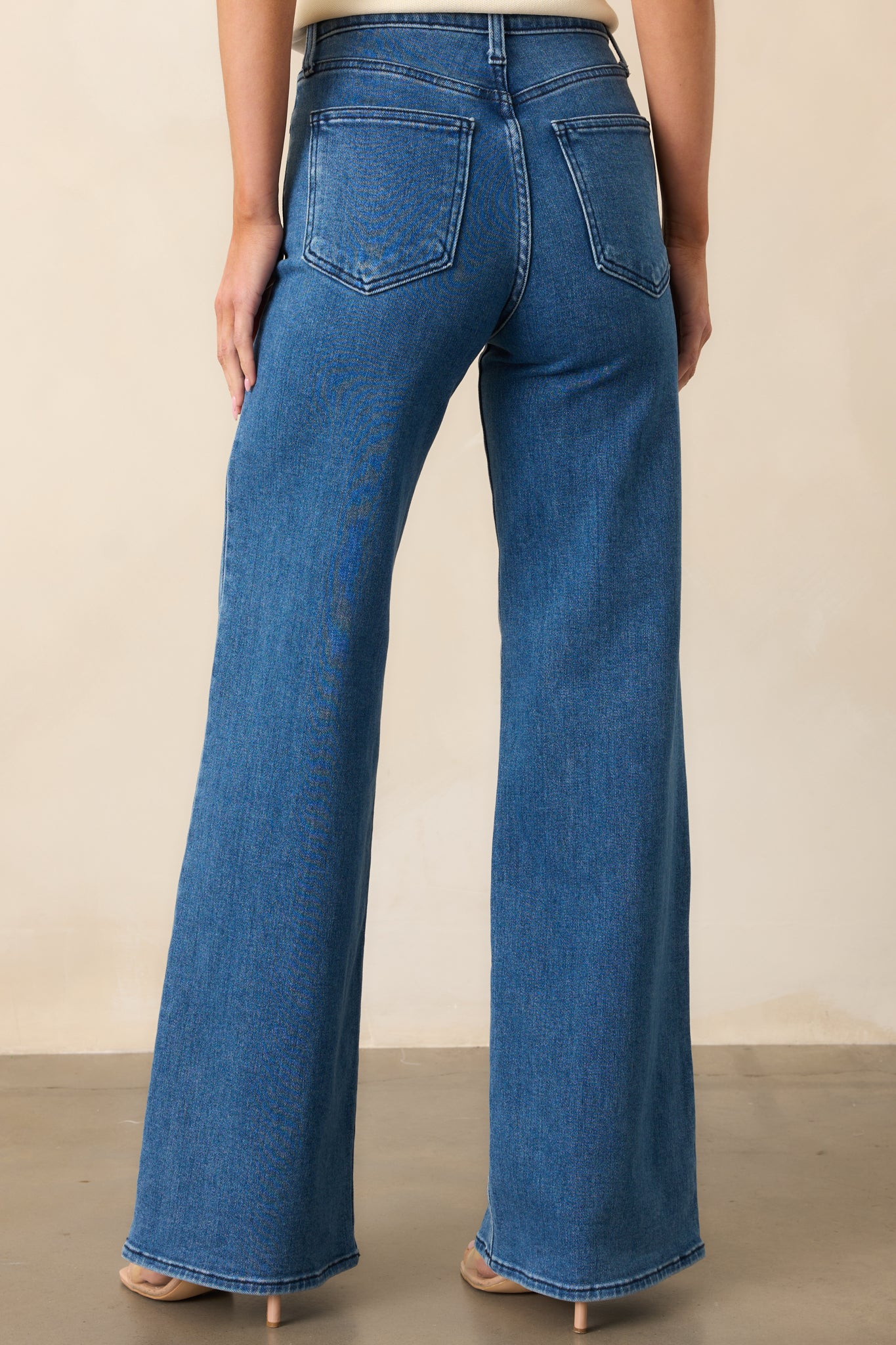A view of the medium wash jeans from the back, featuring functional back pockets and a flattering high-rise fit.