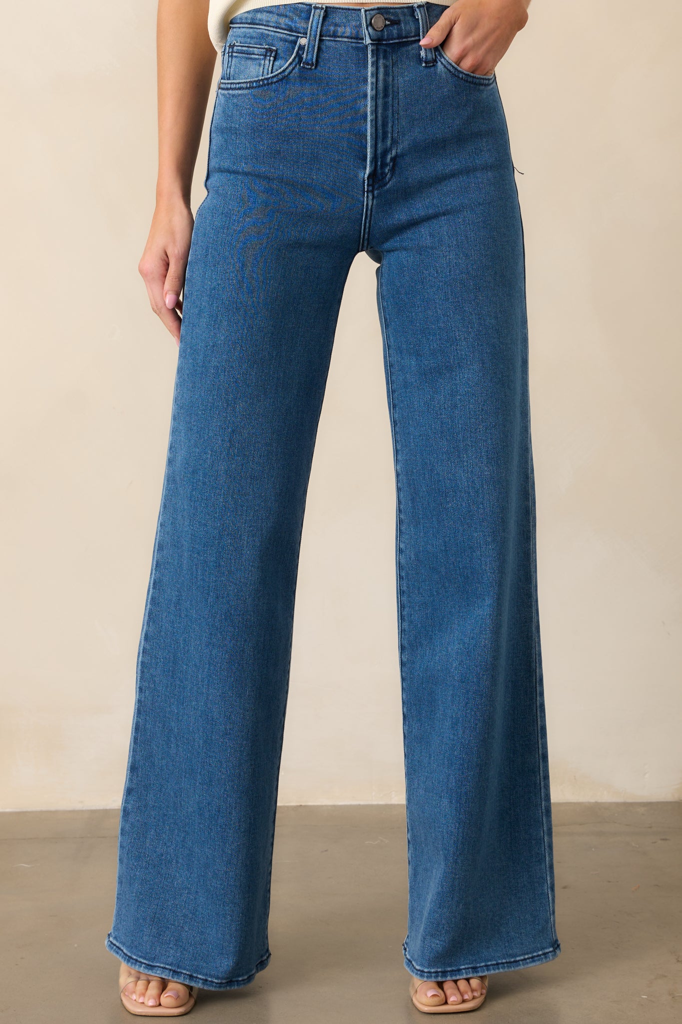 A close-up of the jeans’ high-rise waistband and zipper button closure, highlighting the classic denim style.