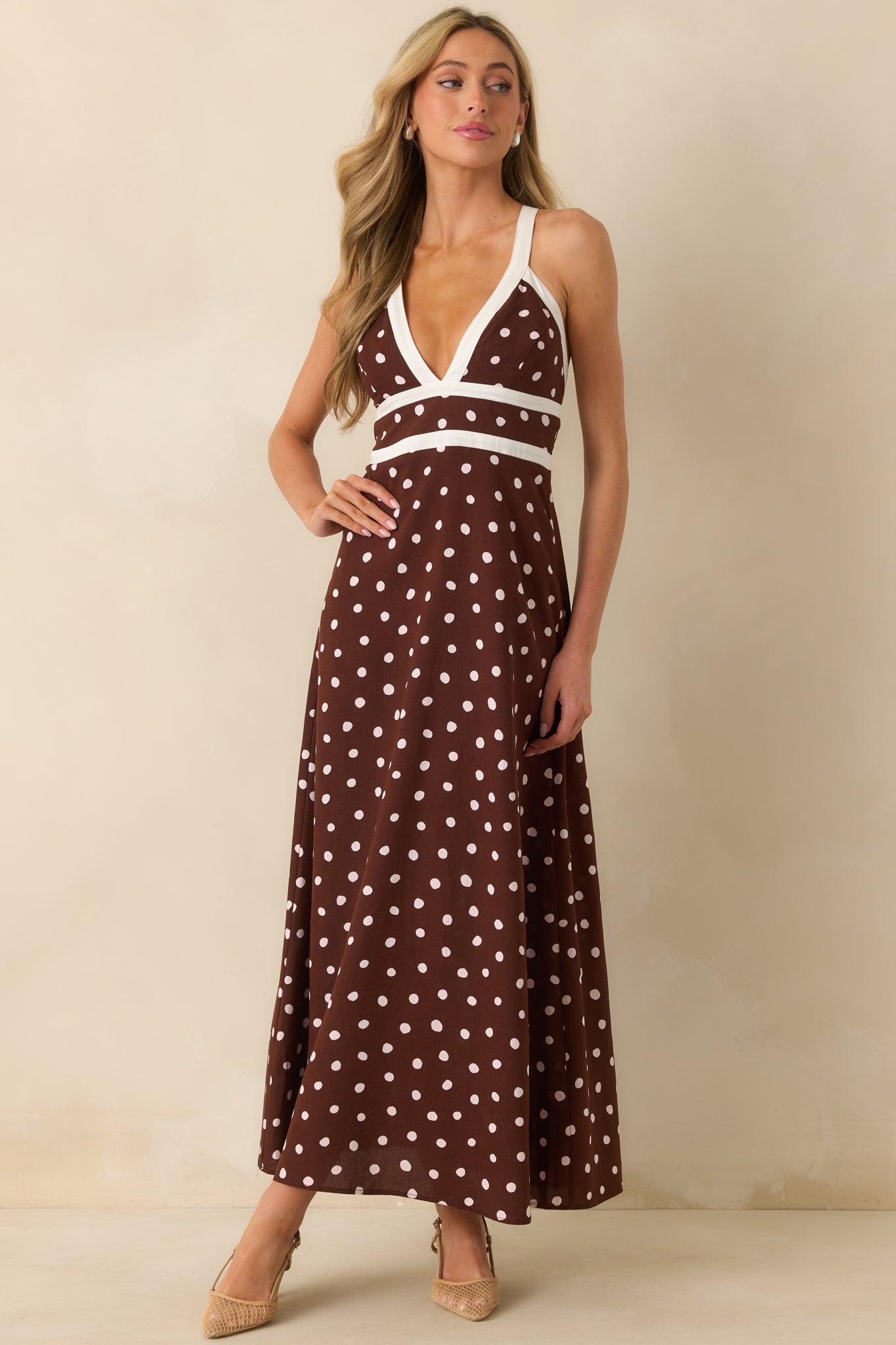 Angled front shot emphasizing deep v-neckline, polka dot pattern, and trim along the neckline.