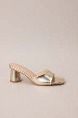 Side view of these gold heels with square toe, slip-on design, strap over foot, short circular heel.