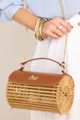 Angled side view of this bamboo handbag that features a top handle, a single flap design, a twist lock closure, and a removable chain strap.
