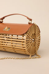 Side view of this bamboo handbag that features a top handle, a single flap design, a twist lock closure, and a removable chain strap.