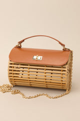 This bamboo handbag features a top handle, a single flap design, a twist lock closure, and a removable chain strap.