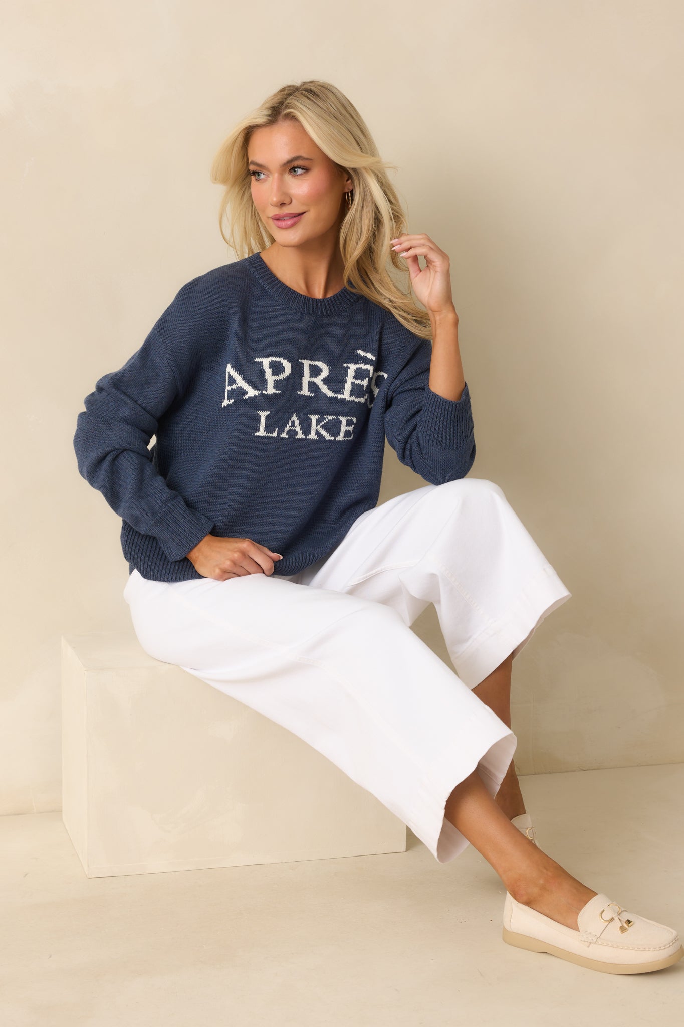 Navy knit pullover sweater with ribbed trim and bold white "Après Lake" lettering displayed across the front.