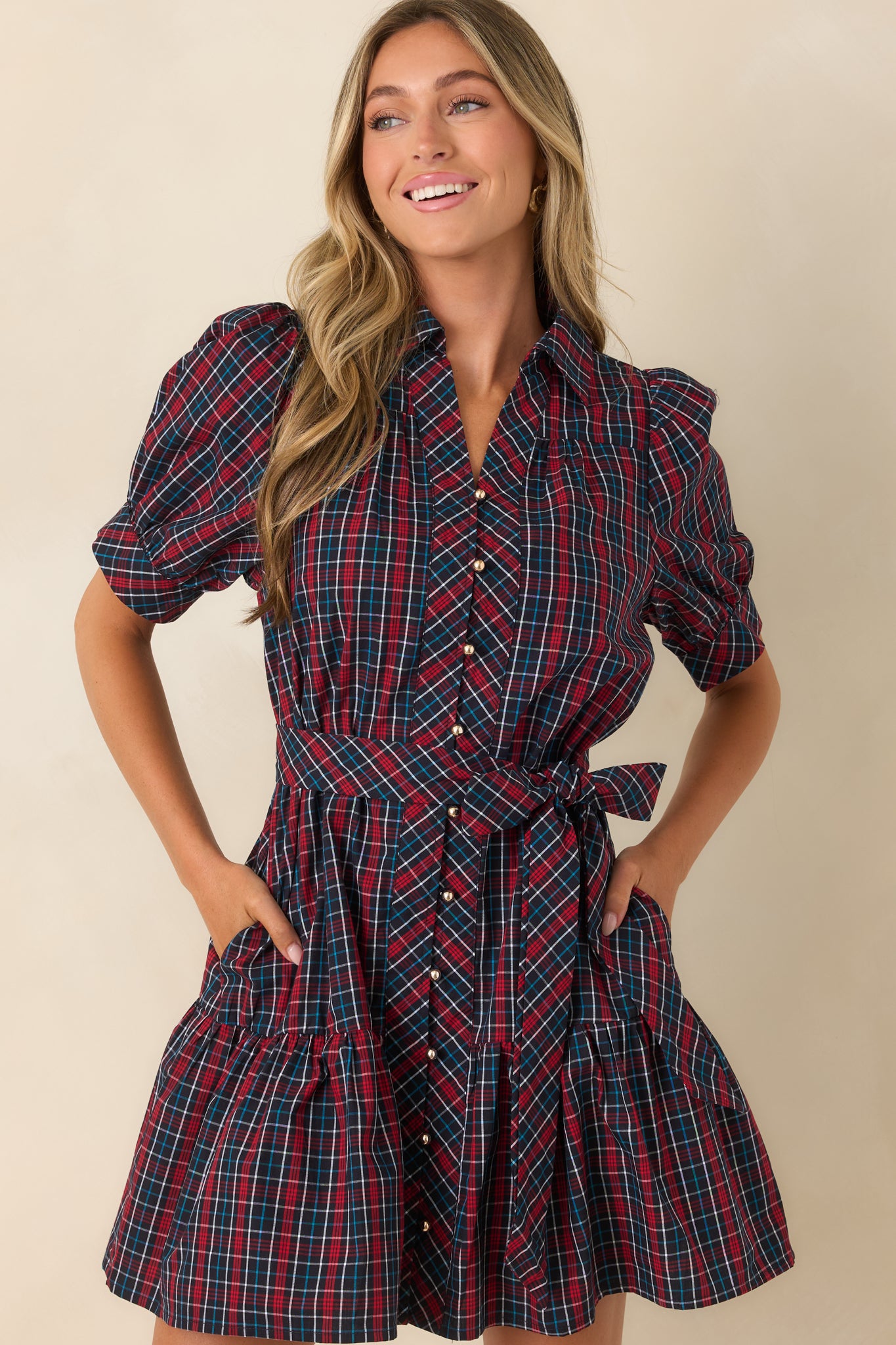 Close-up of navy and red plaid mini dress with puff sleeves, gold-tone buttons, and tie waist.