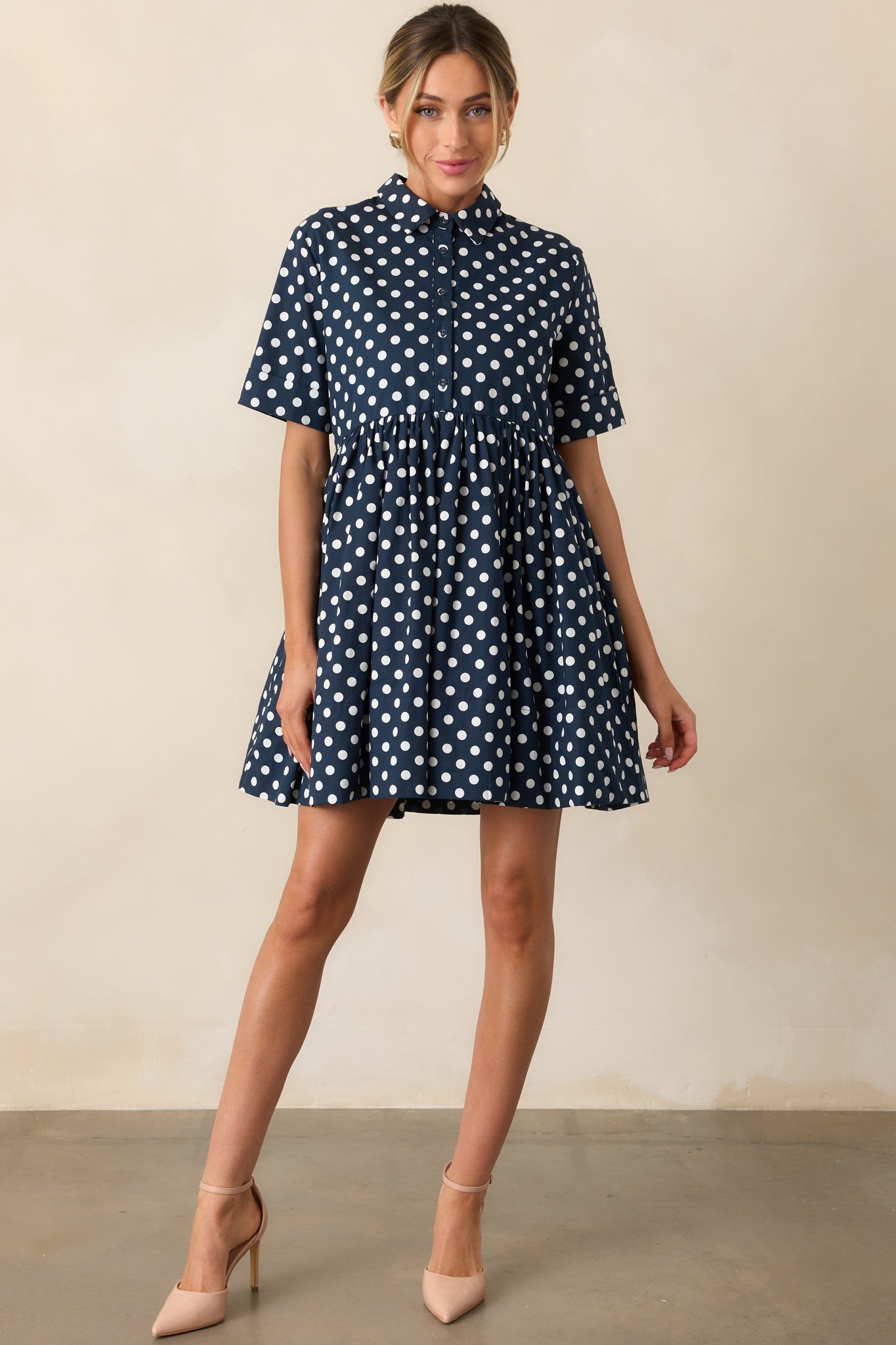 Navy and white polka dot dress with collared neckline and pockets displayed from the front.