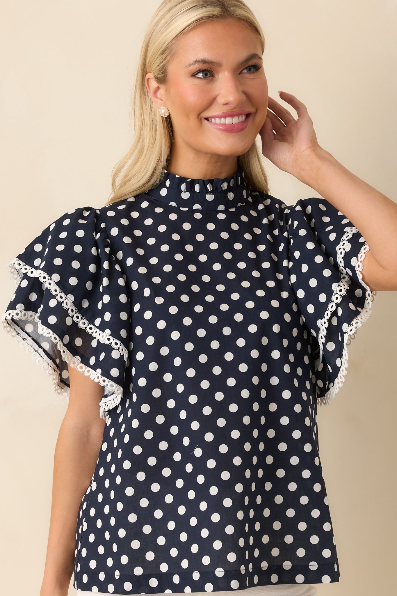 Cropped view highlighting the texture and delicate eyelet trimming on the ruffle neckline of the polka dot top.