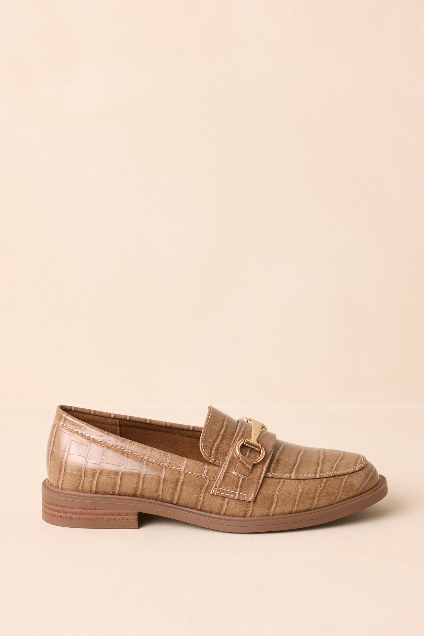 Full side view of the loafers against a beige background, showing the low stacked heel.