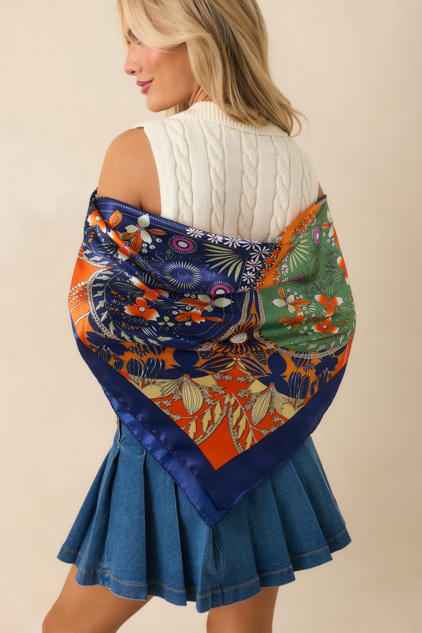 Orange hair scarf seen from behind, displaying geometric patterns, four-leaf clover details, and a glossy satin finish.