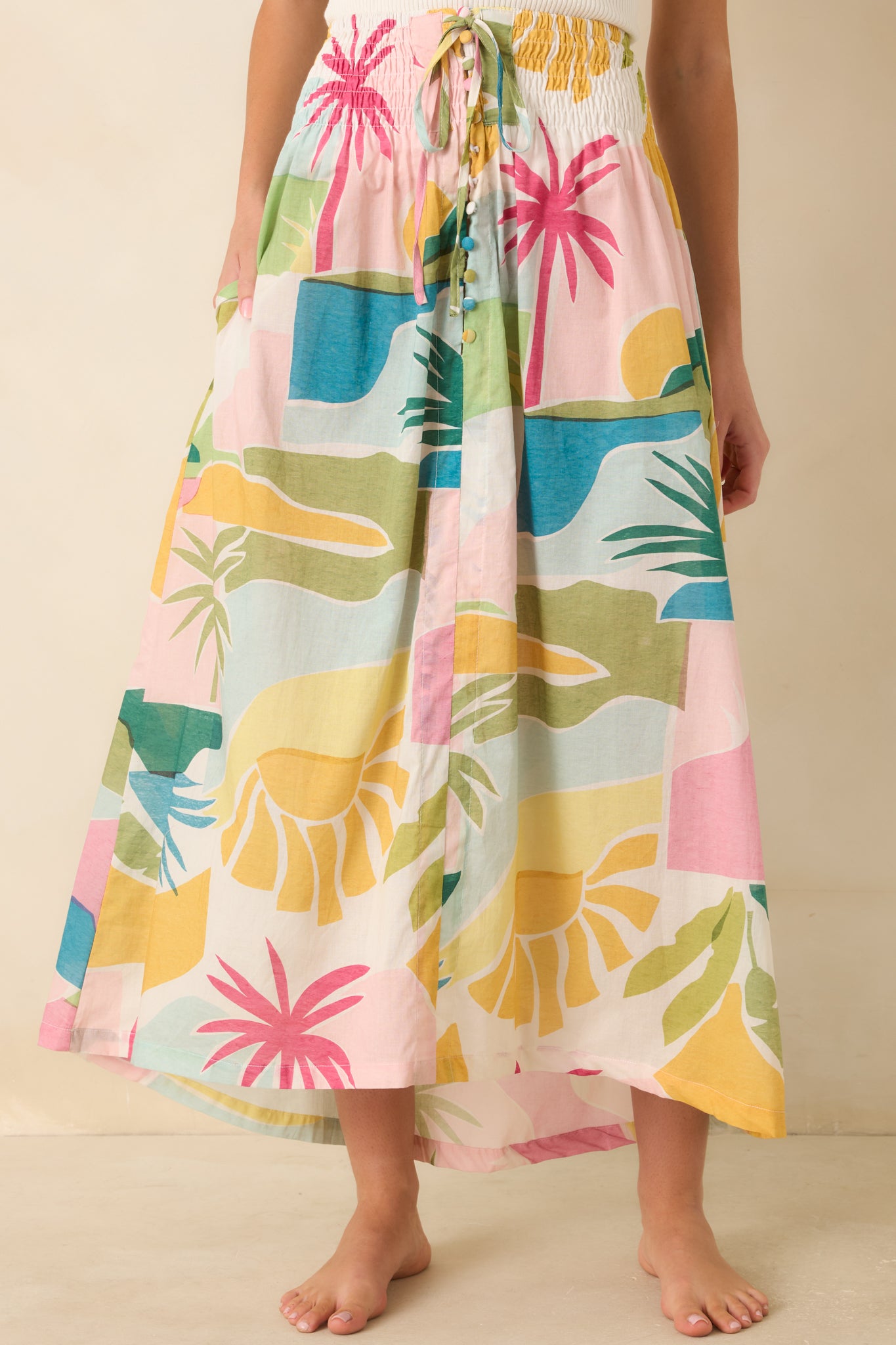 Close-up of the Paradisa tropical print maxi skirt highlighting the smocked elastic waistband, adjustable drawstring tie with beaded accents, and colorful tropical print.