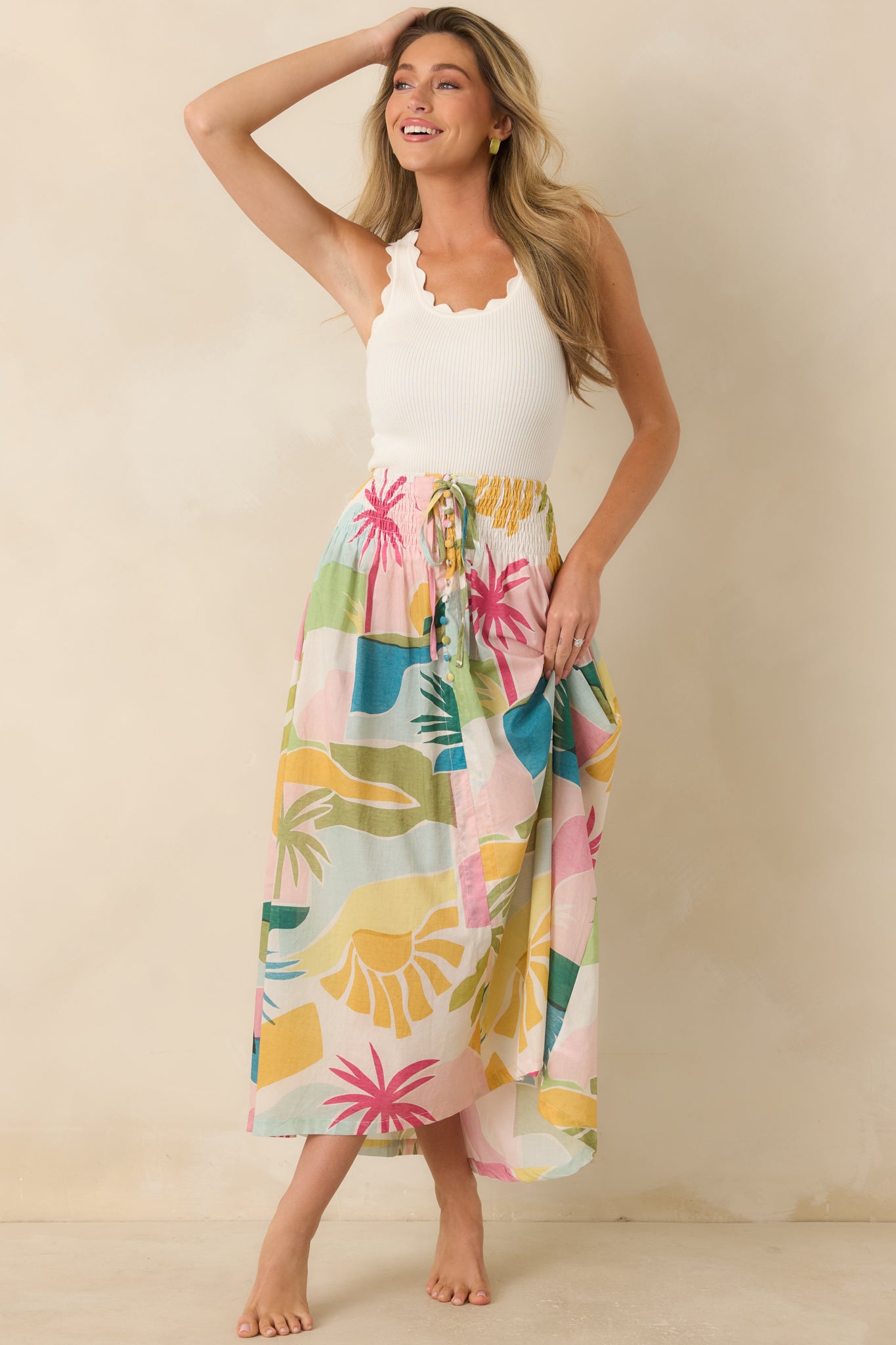 Front view of the Paradisa tropical print maxi skirt featuring a smocked waistband, drawstring tie with beaded accents, and a colorful palm tree print.