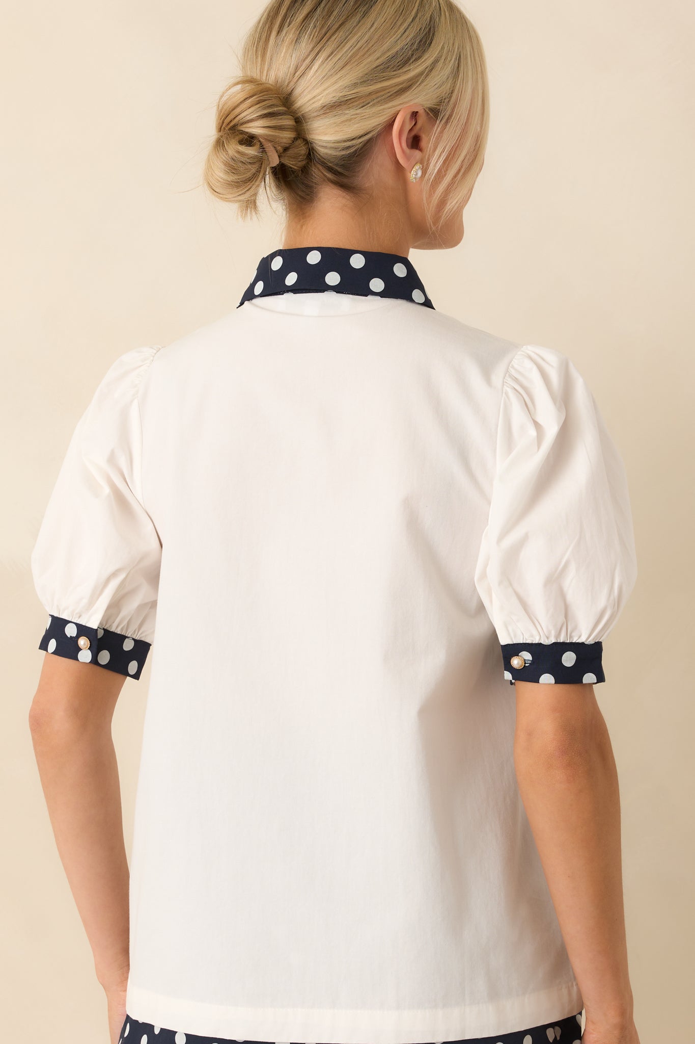 Rear view of the white top with plain back and smooth cotton fabric, showing cuffed short sleeves from behind.