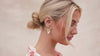 Woman swiping her hair behind her ear and wearing a gold floral earring.