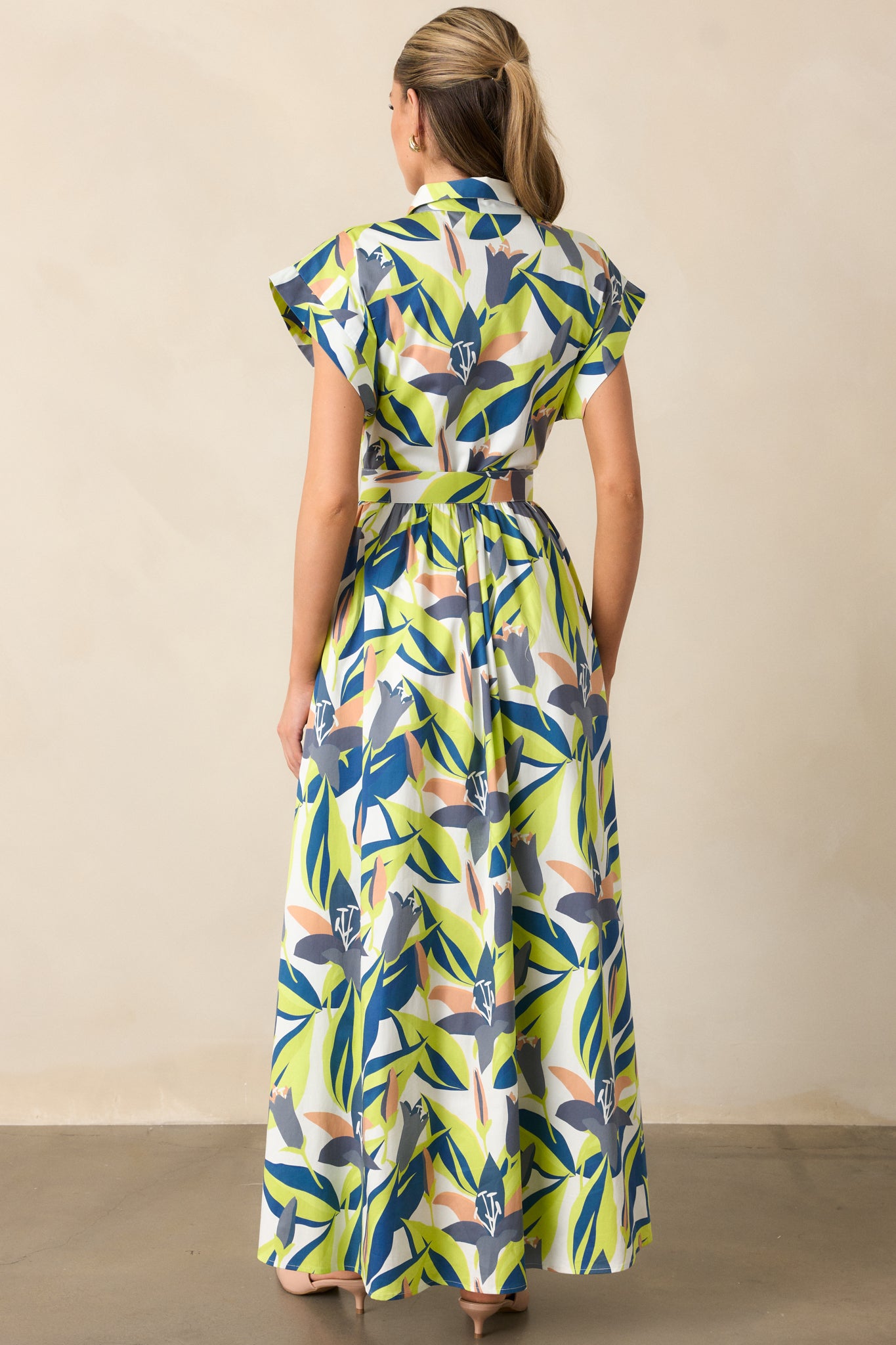 Back view of maxi dress with cuffed short sleeves, optional belt, and full white lining visible under the multicolor floral print.