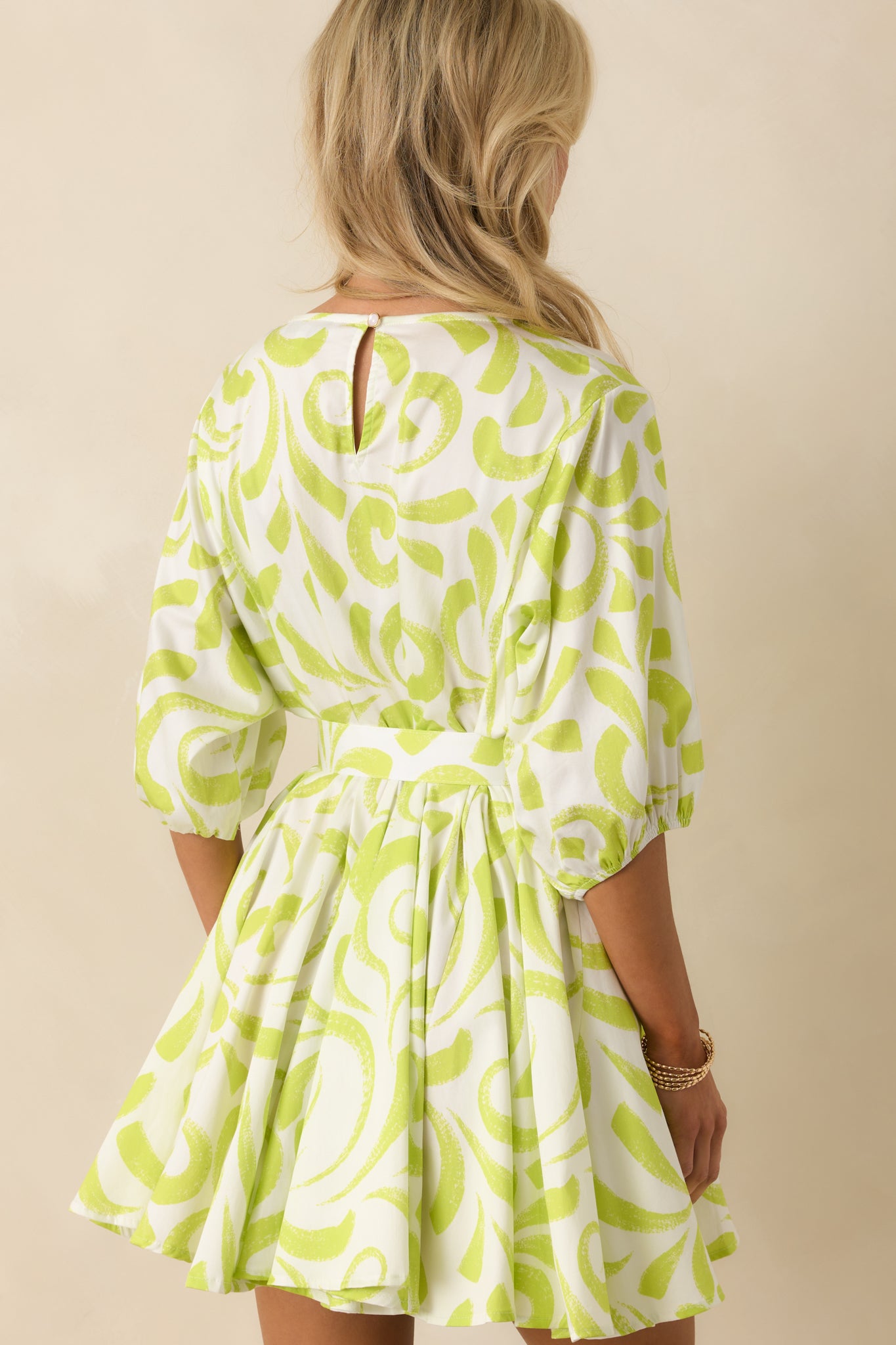 Rear view of the mini dress showcasing the back keyhole closure and elastic sleeve cuffs.