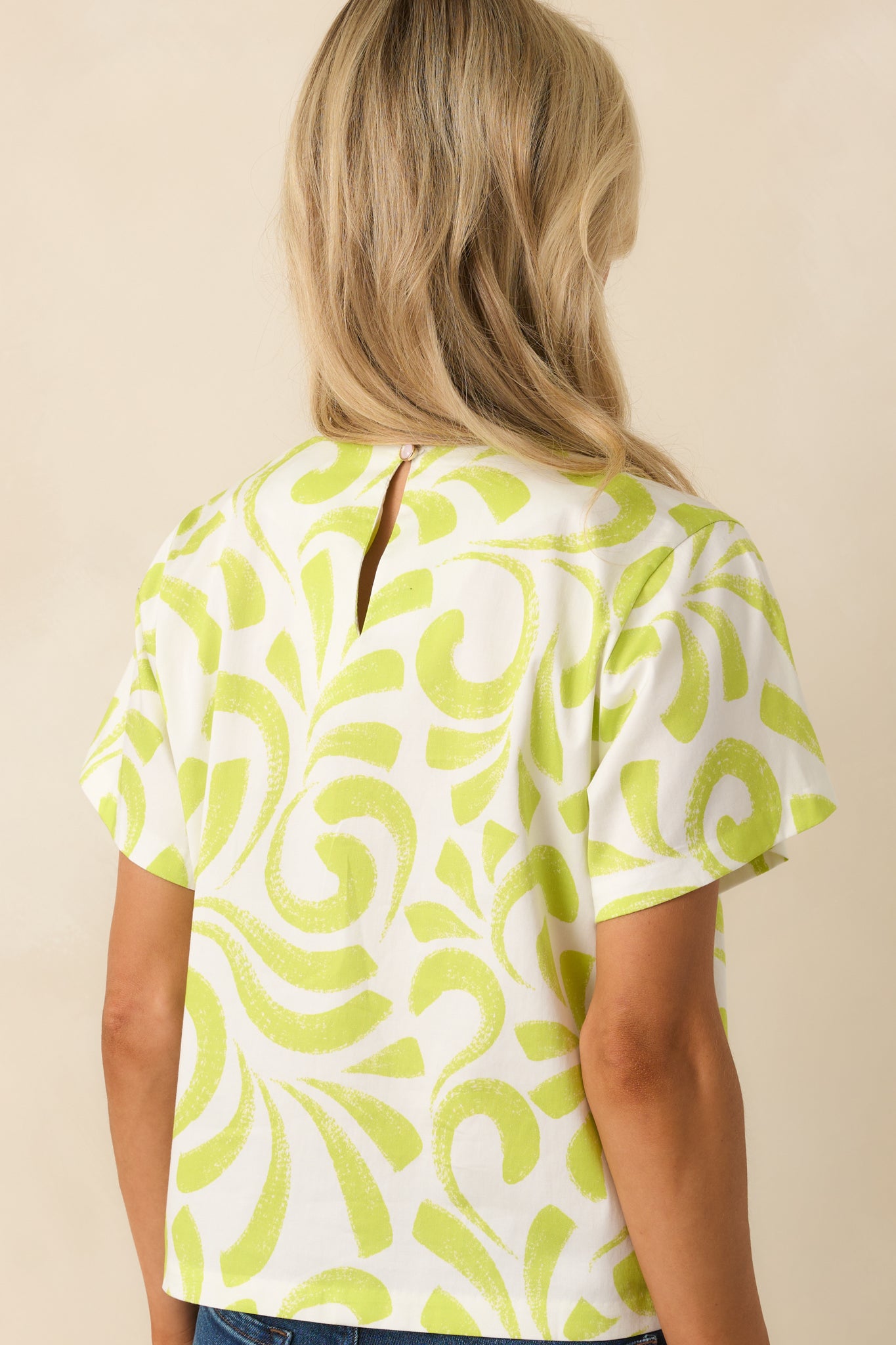 Back view of short-sleeve top with keyhole button closure, boxy silhouette, and lightweight cotton fabric.